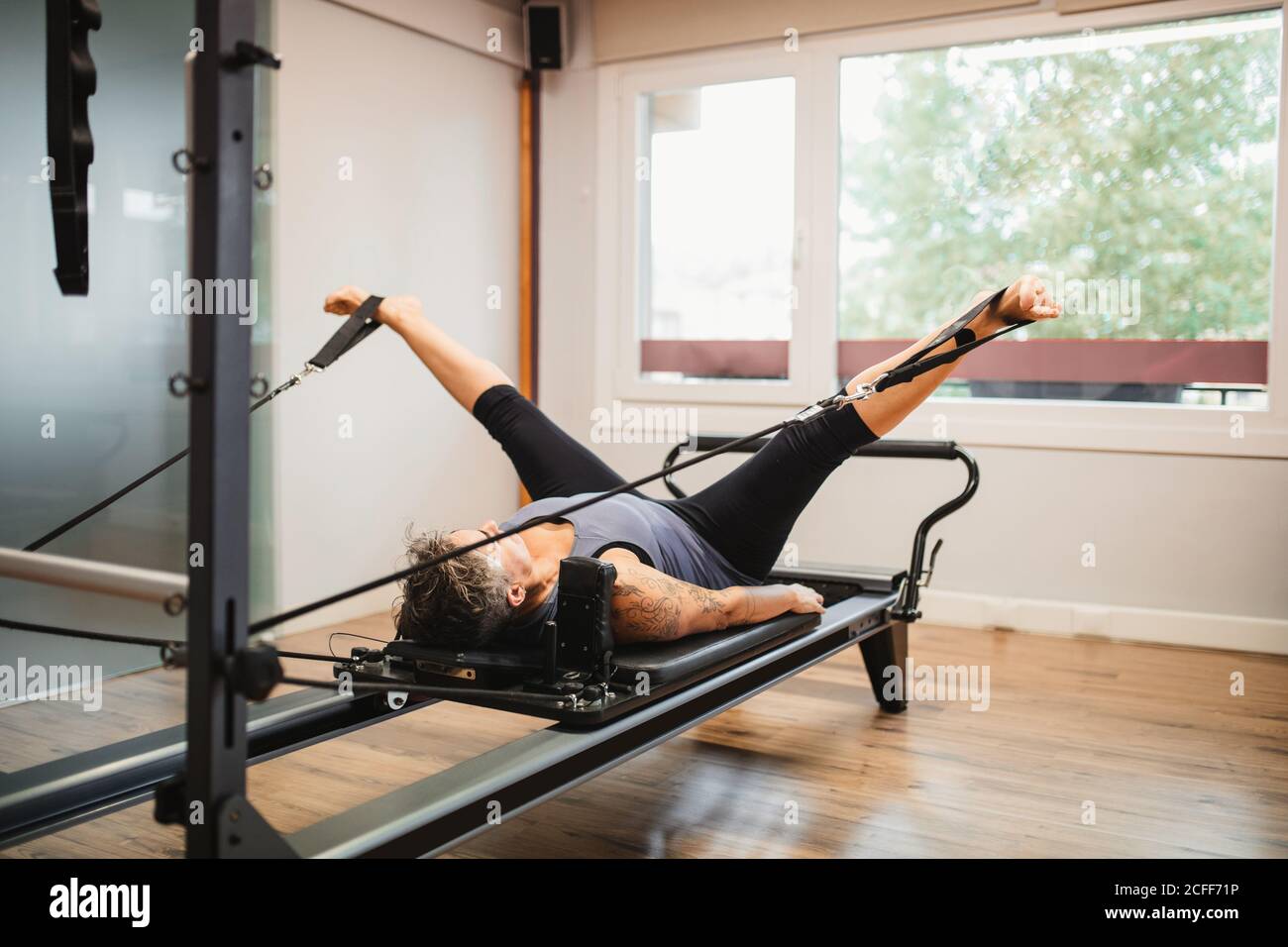 Femme adulte dans les vêtements de sport allongé sur la machine de pilates  et d'étirement jambes avec bandes de résistance pendant l'entraînement dans  la salle de gym moderne Photo Stock - Alamy