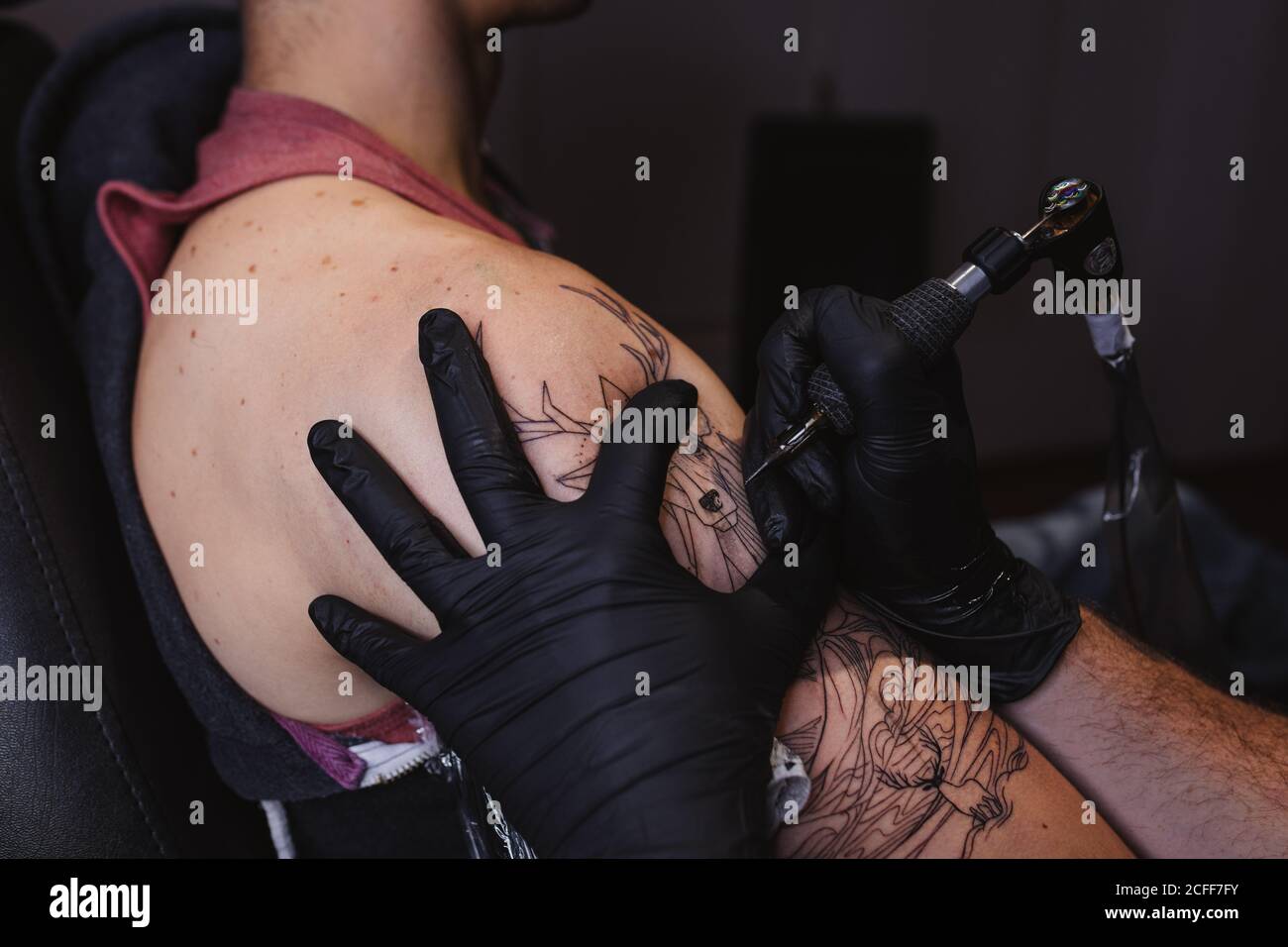 Maître faisant tatouage sur l'avant-bras du client mâle Banque D'Images