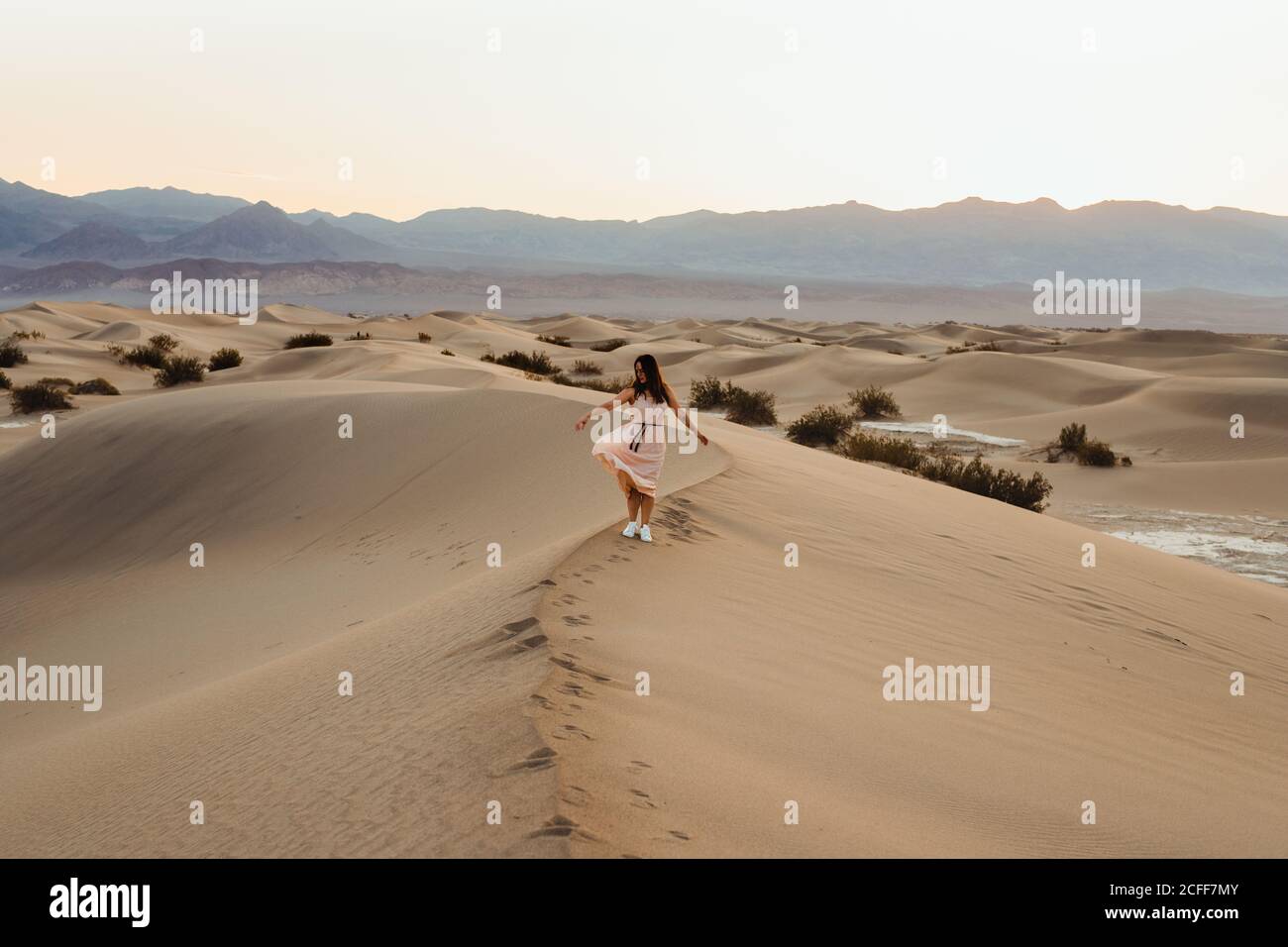 Vue arrière de la jeune femme marchant dans le désert laissant des empreintes de pas dans les dunes de sable sec de la vallée de la mort Banque D'Images