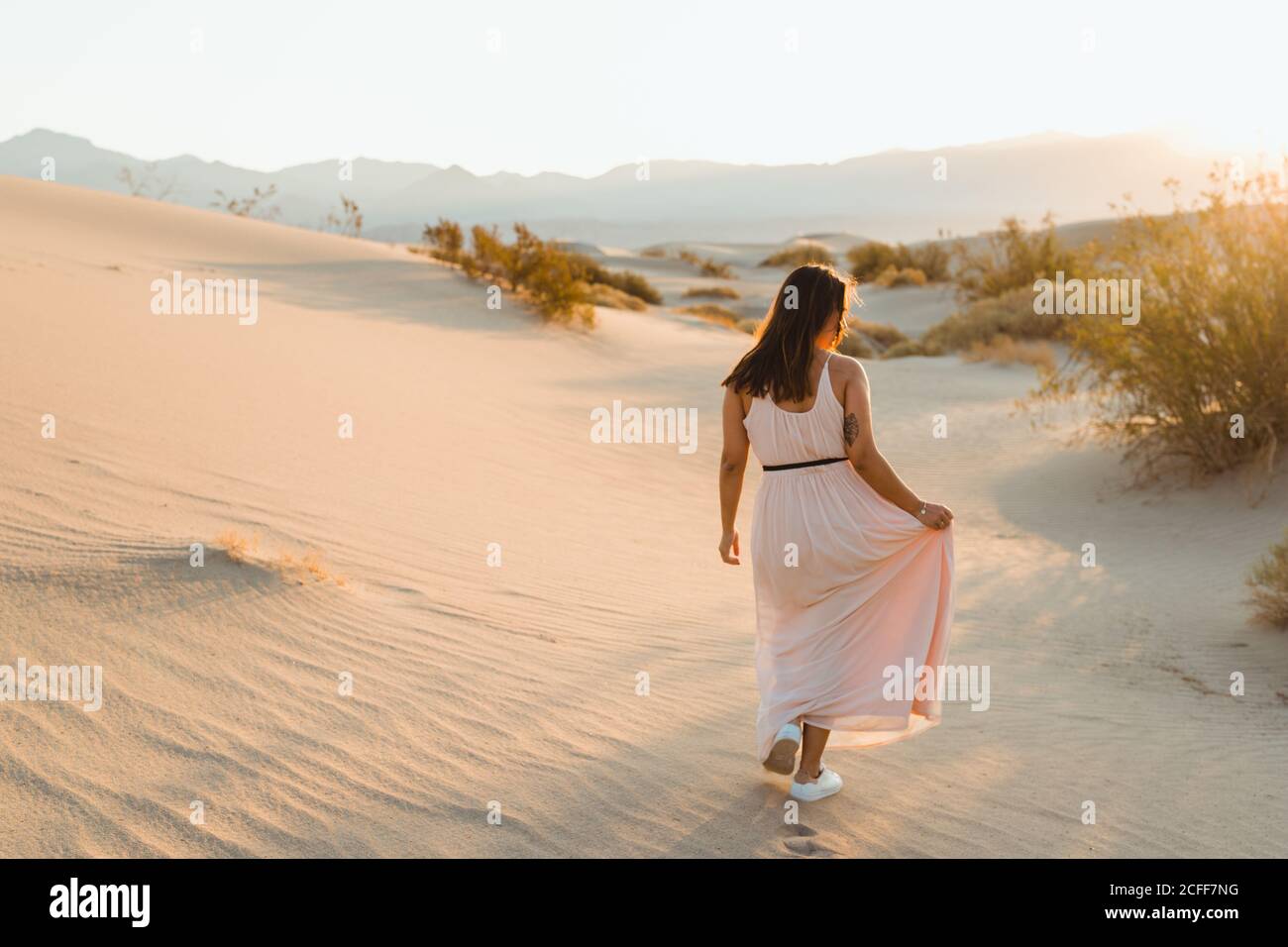 Vue arrière de la jeune femme marchant dans le désert laissant des empreintes de pas dans les dunes de sable sec de la vallée de la mort Banque D'Images