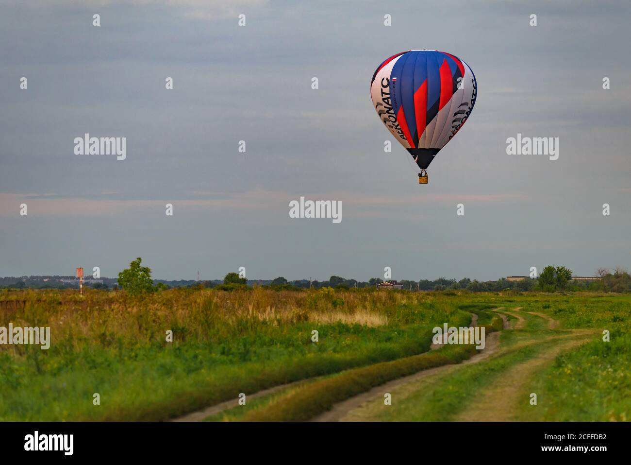 RYAZAN, RUSSIE - 16 AOÛT 2020 : ballon d'air chaud survolant un champ et une route de campagne au crépuscule Banque D'Images