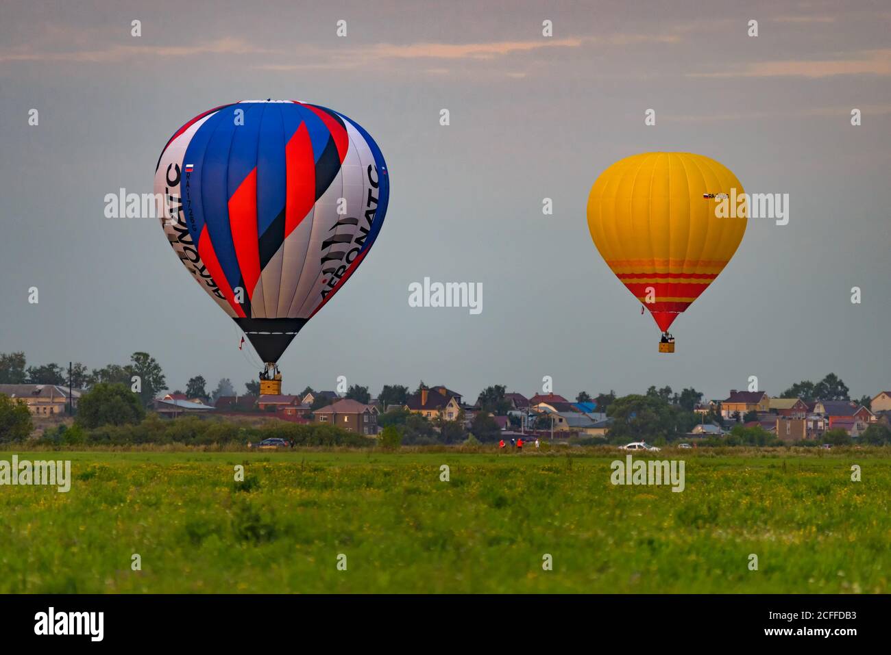 RYAZAN, RUSSIE - 16 AOÛT 2020 : deux ballons d'air chaud survolant un champ au crépuscule avec un village en arrière-plan Banque D'Images