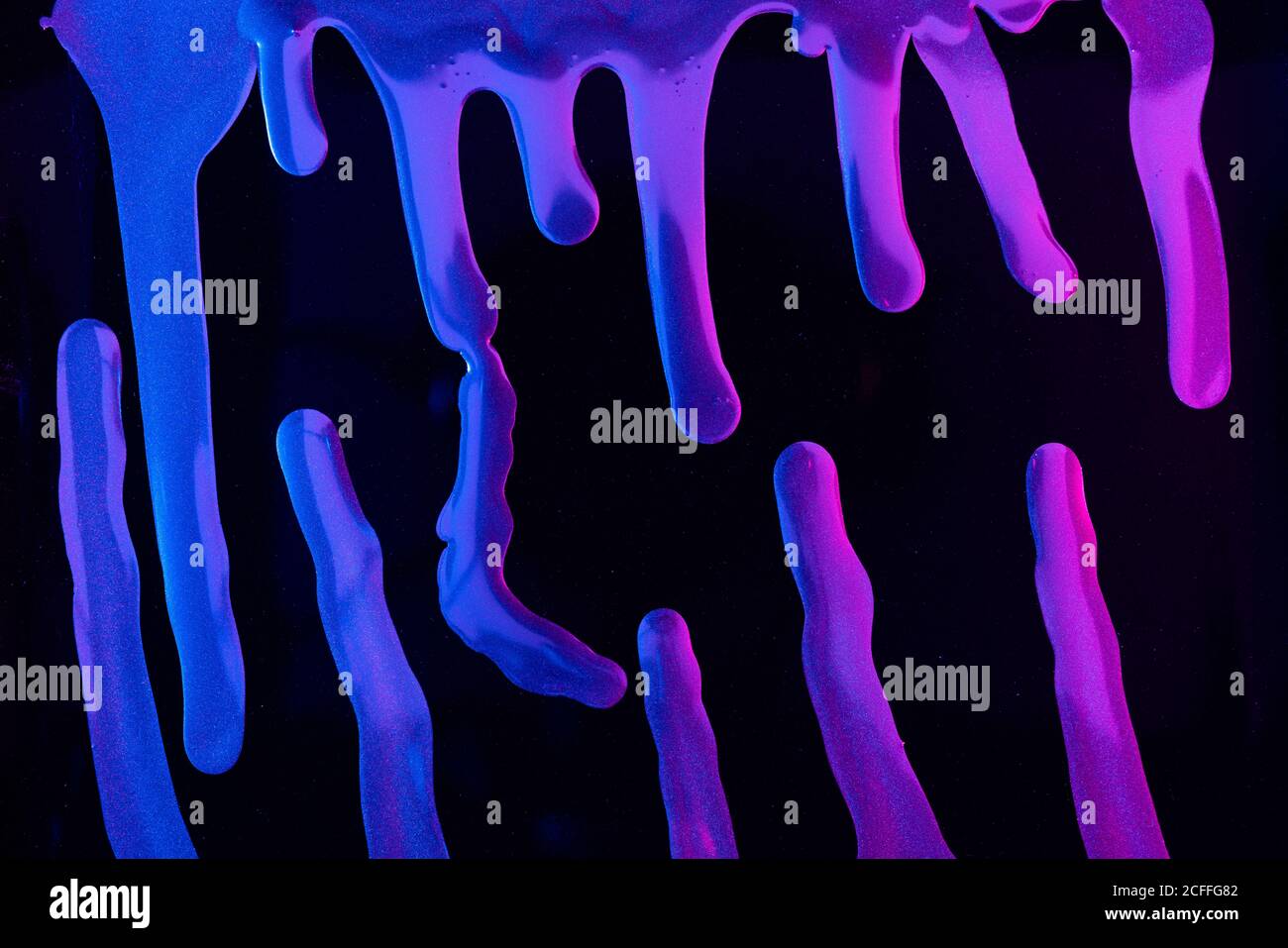 Gros plan de taches de pigment néon brillant flottant sur fond noir Banque D'Images