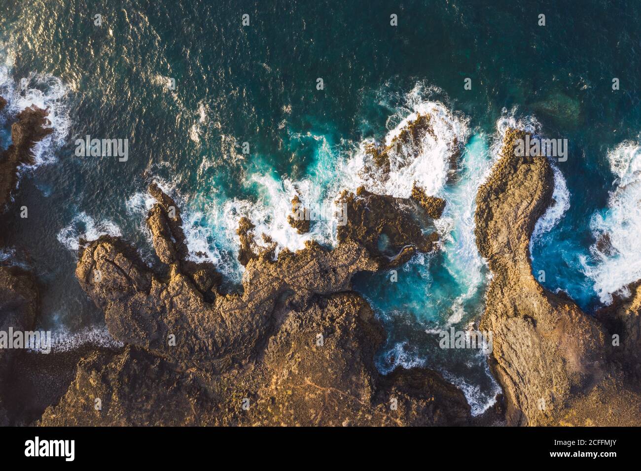Vue aérienne de la côte rocheuse de l'Espagne avec des montagnes majestueuses vagues de mousse sous la lumière du soleil Banque D'Images
