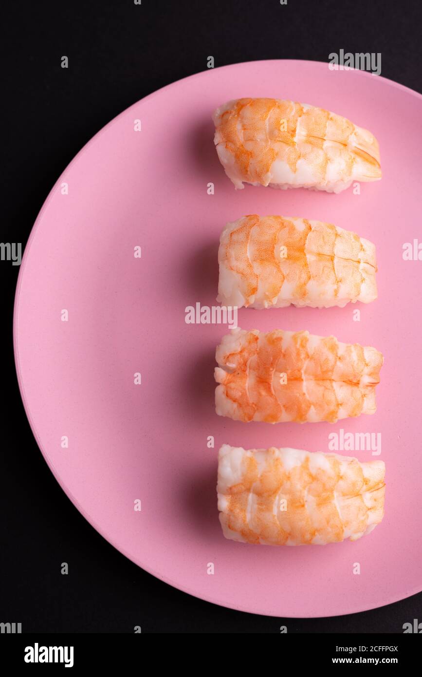 Vue de dessus de l'ensemble de sushis EBI Nigiri servis sur plaque sur fond sombre en studio Banque D'Images