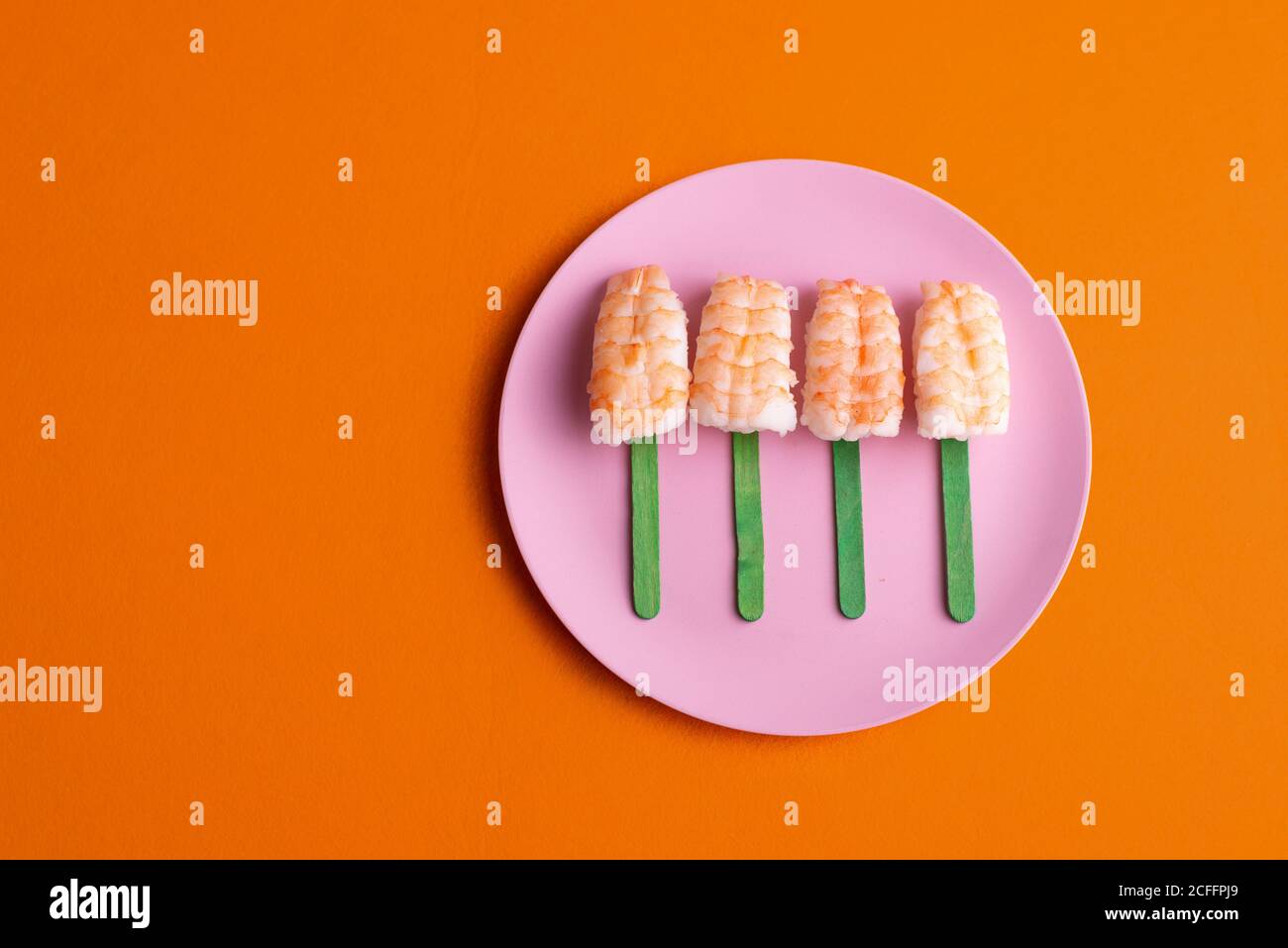 Vue de dessus de l'ensemble de sushi EBI Nigiri avec crevettes servies en forme de popsicle et placées sur l'assiette sur fond orange en studio Banque D'Images