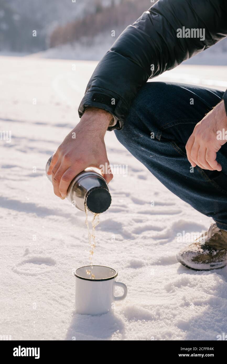 homme qui verse du thé à la bouteille de thermos le jour de l'hiver Banque D'Images