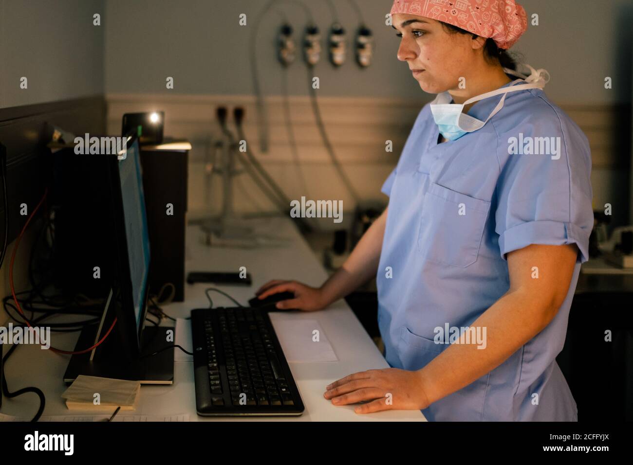 Vue latérale d'une femme médecin utilisant un ordinateur pendant le travail en laboratoire de l'hôpital moderne Banque D'Images