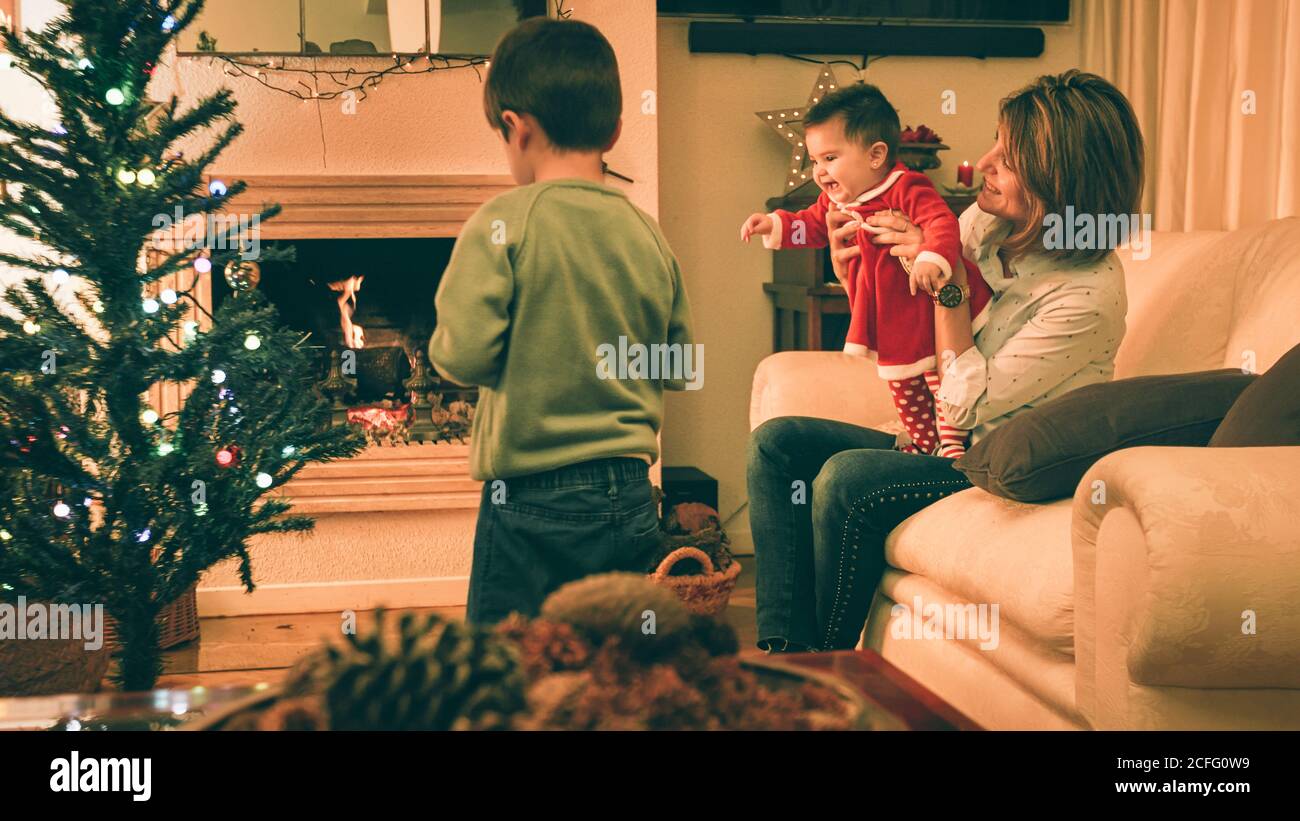 Mère jouant avec bébé tandis que son décorant arbre de Noël Banque D'Images