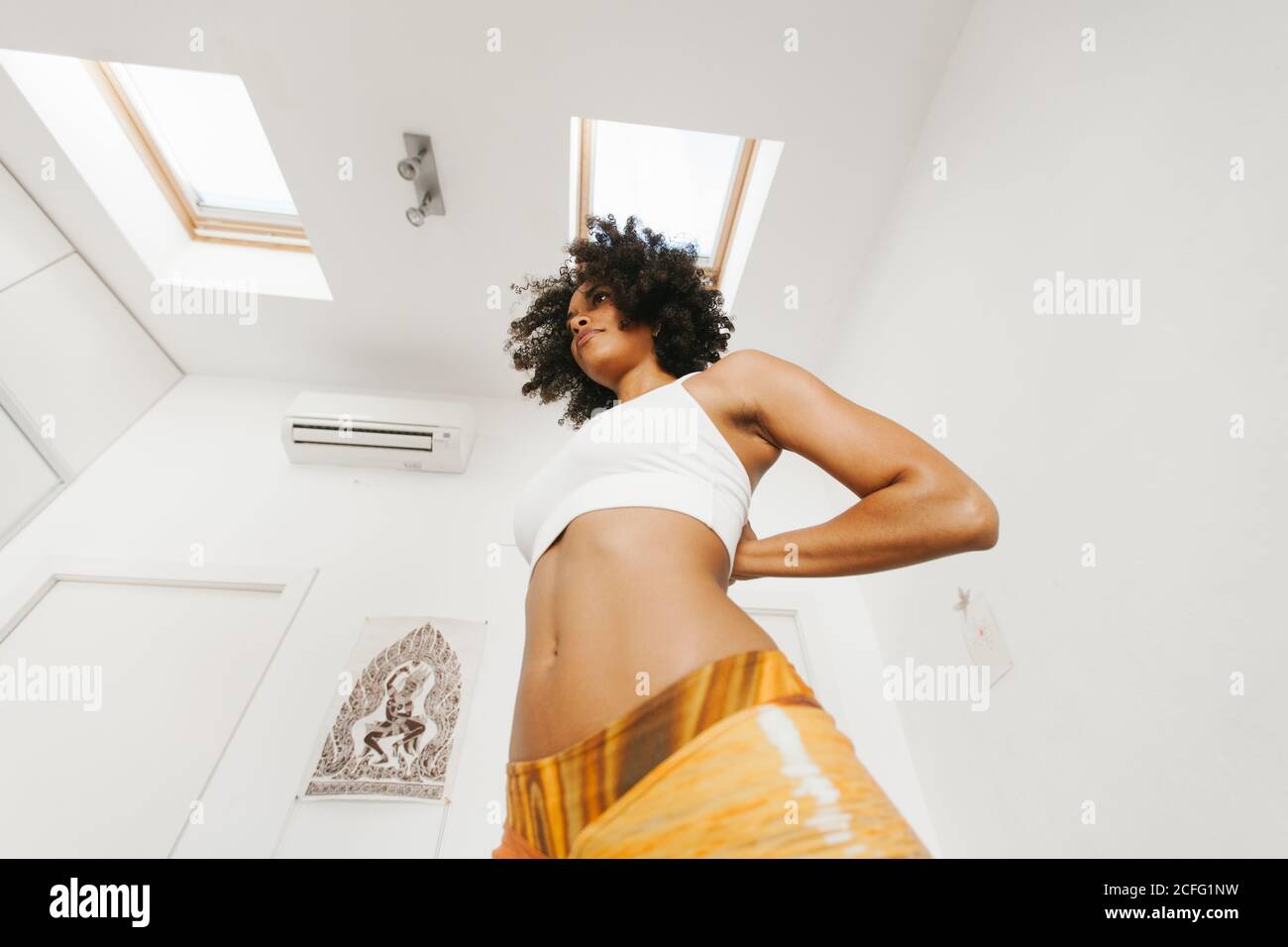 Depuis le dessous de l'Afro-américain jeune femme attrayante exécutant la posture de yoga avec les mains repliées derrière le dos dans la pièce lumineuse Banque D'Images
