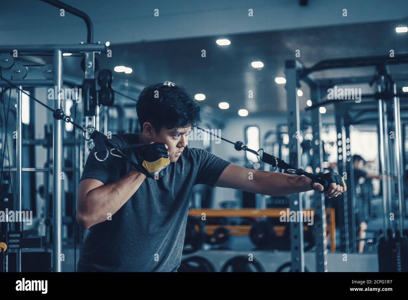 Un homme qui travaille sur sa poitrine avec Cable Crossover dans la salle de gym. Concept de fitness, d'entraînement, de sport et de santé. Banque D'Images