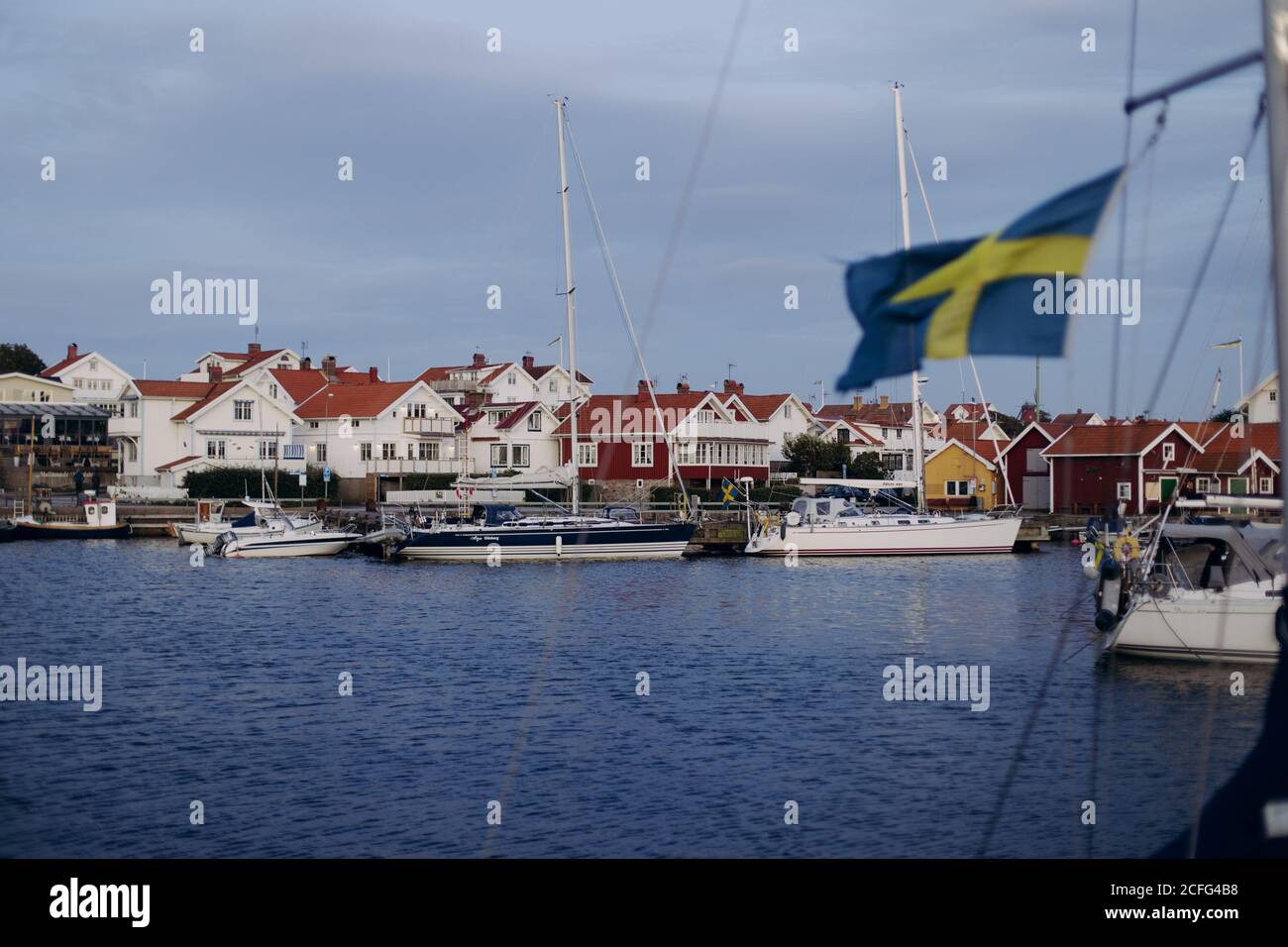 Port de plaisance avec yachts blancs parking à la jetée sur le calme l'eau de mer sur le fond de la petite ville côtière avec nice Maisons et ciel nuageux en Suède Banque D'Images