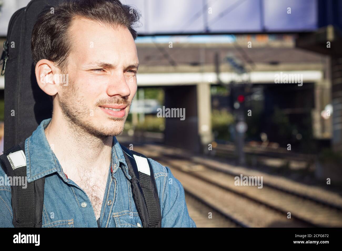 Portrait d'un jeune homme qui s'accroupse en train sur la plate-forme, en train de s'élancer dans la patience Banque D'Images