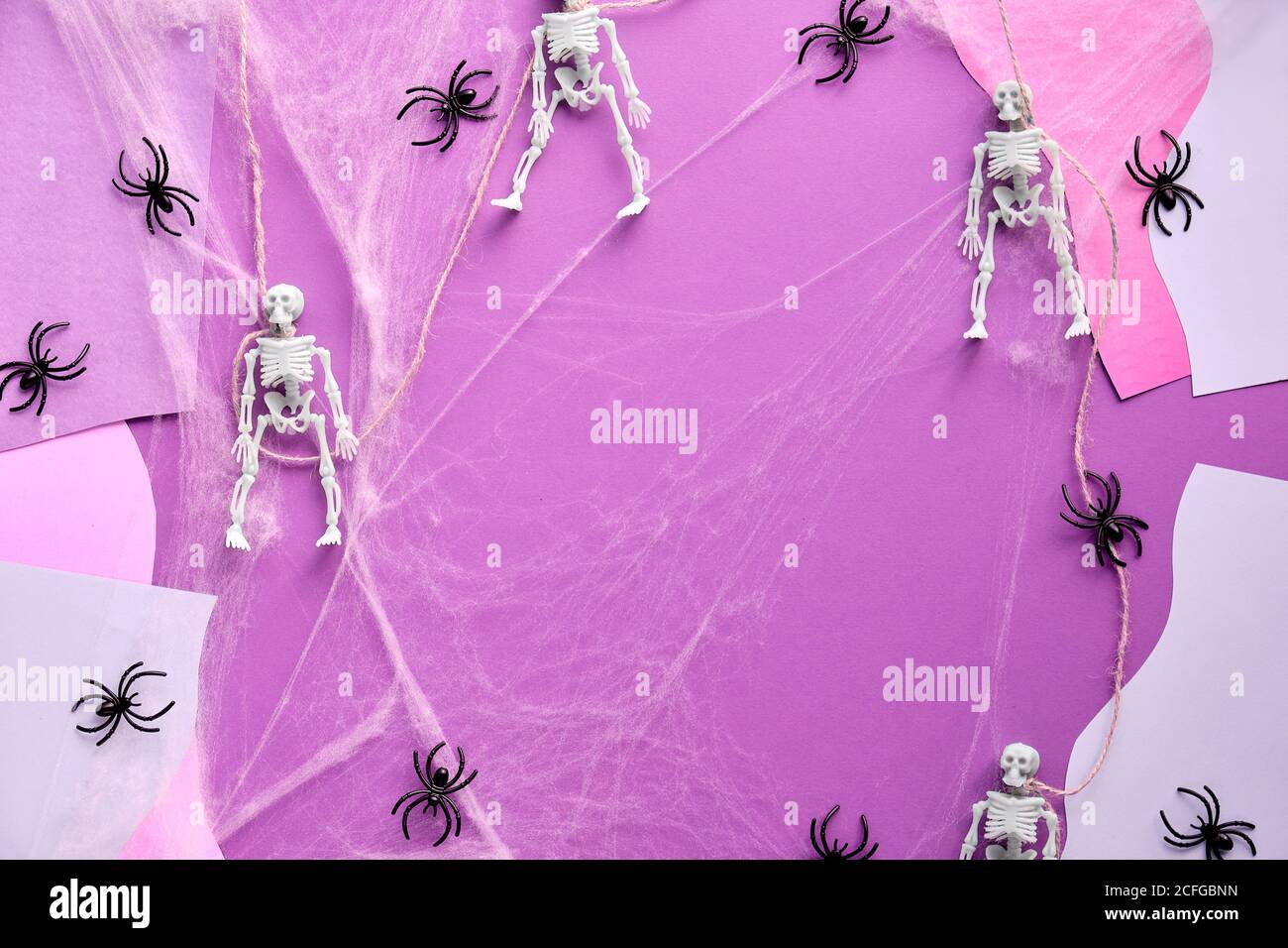 Diviser le fond de papier d'Halloween avec des squelettes, une toile d'araignée et des araignées sur fond abstrait rose et blanc. Plan de travail créatif, vue du dessus. Banque D'Images