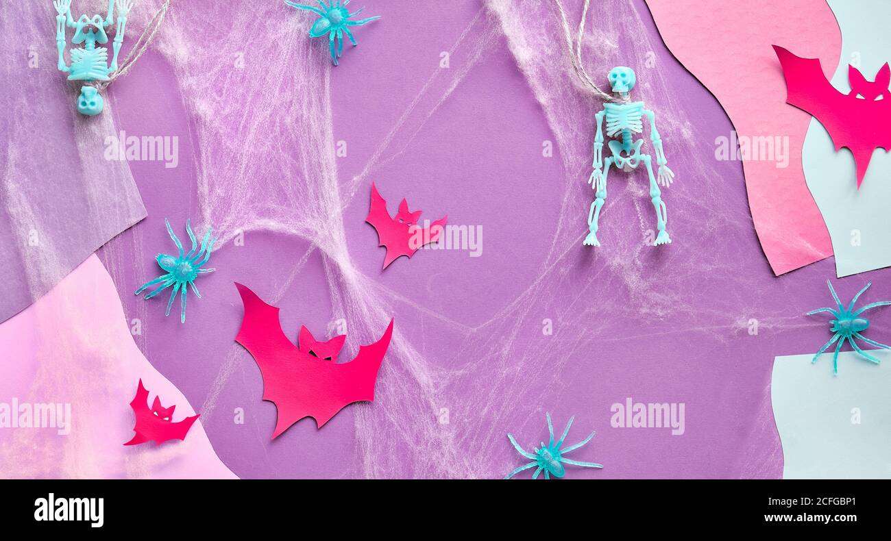 Partager le fond de papier panoramique d'Halloween avec des buts en papier rouge, des squelettes, une toile d'araignée et des araignées sur fond abstrait rose, violet et blanc. Créat Banque D'Images