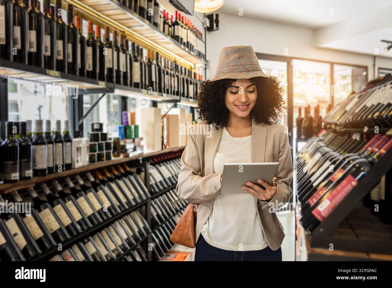 Femme branchée et branchée tenant une tablette sur le marché du vin. Banque D'Images