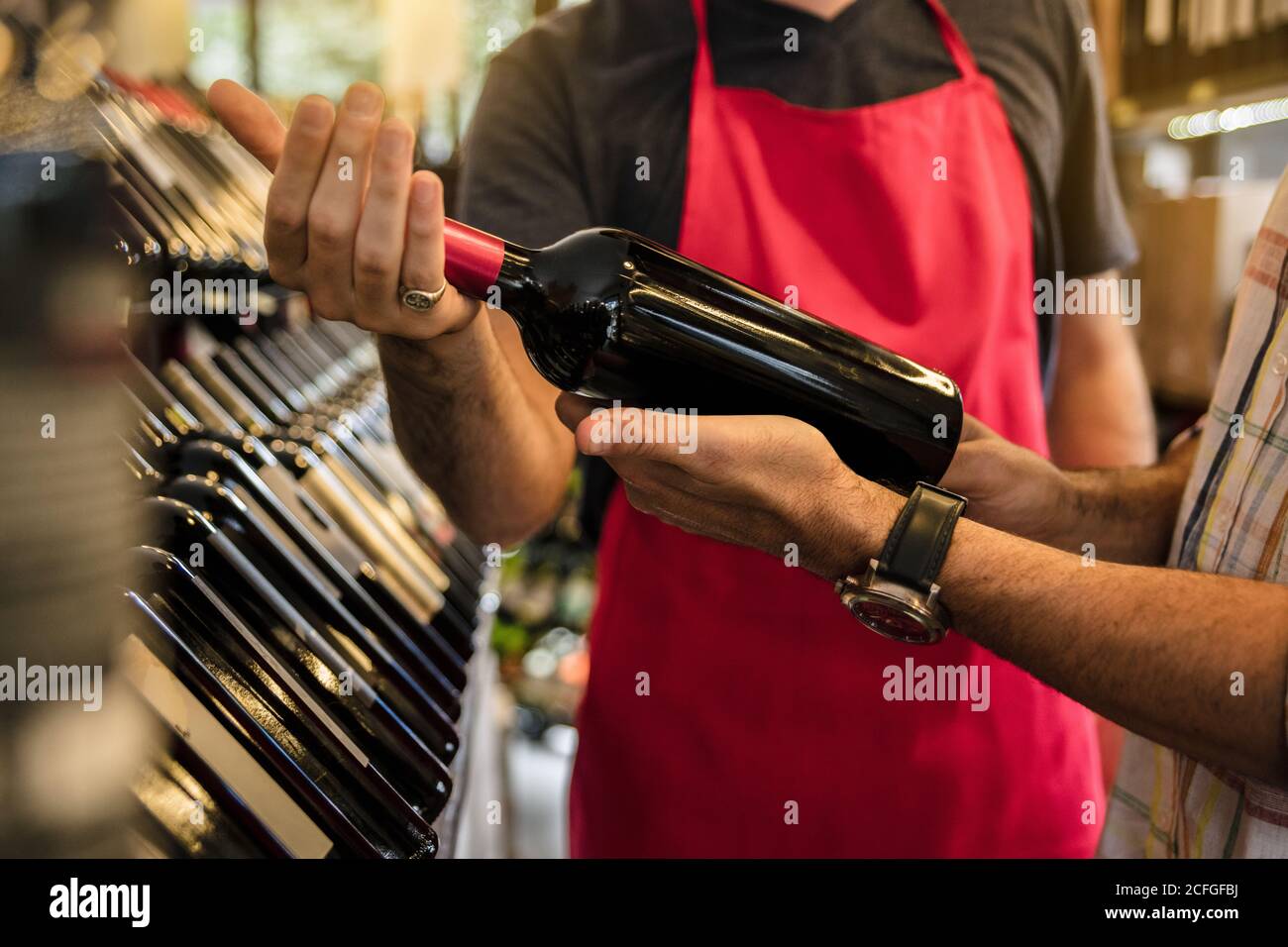 Récolte de l'homme en tablier aidant le client dans le marché du vin avec le choix du vin. Banque D'Images