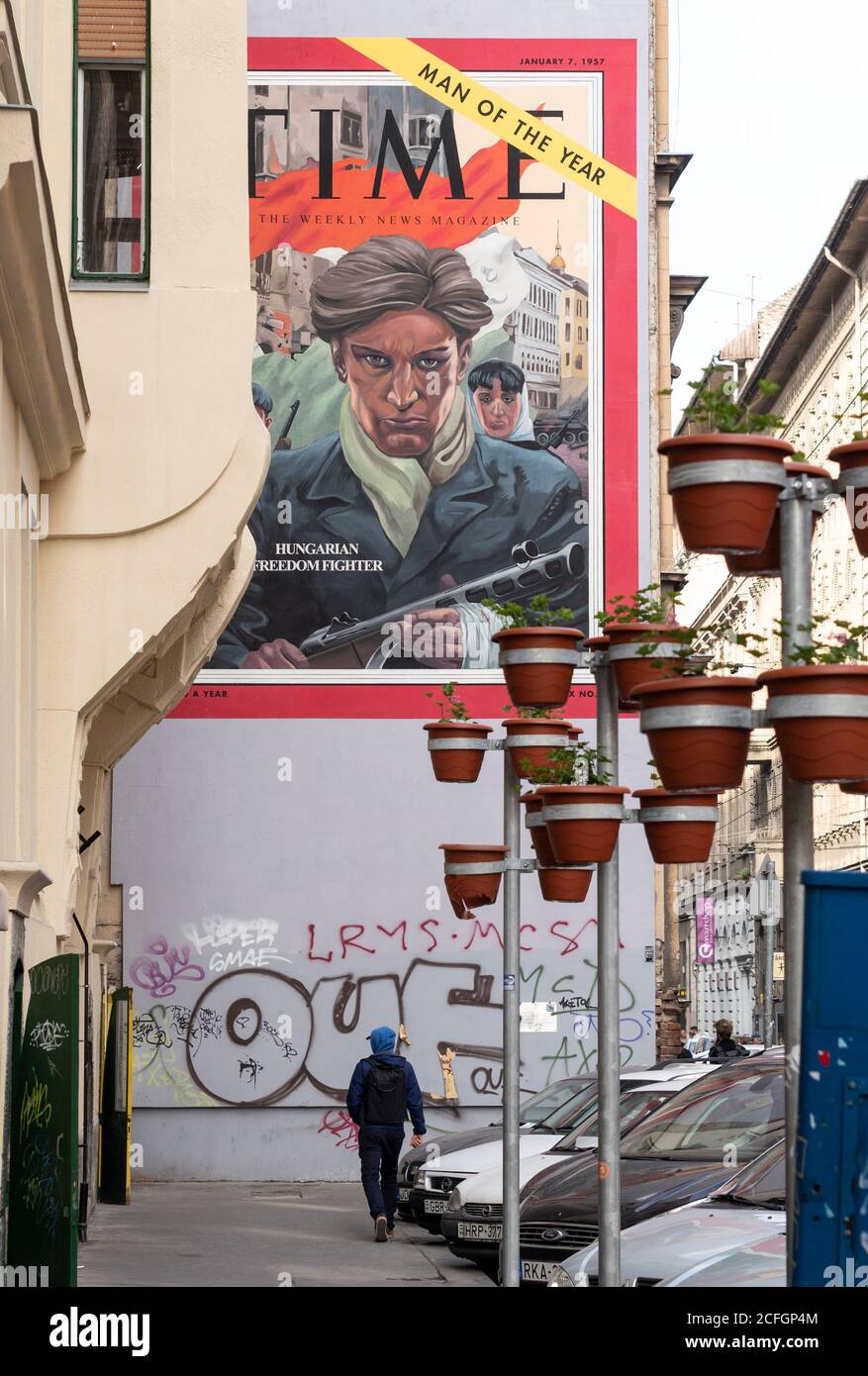 Homme du temps de l'année - Figher de la liberté hongroise : un homme marche vers une murale du 7 janvier 1957 couverture du temps peinte comme une murale sur un mur dans une rue de Pest. Banque D'Images