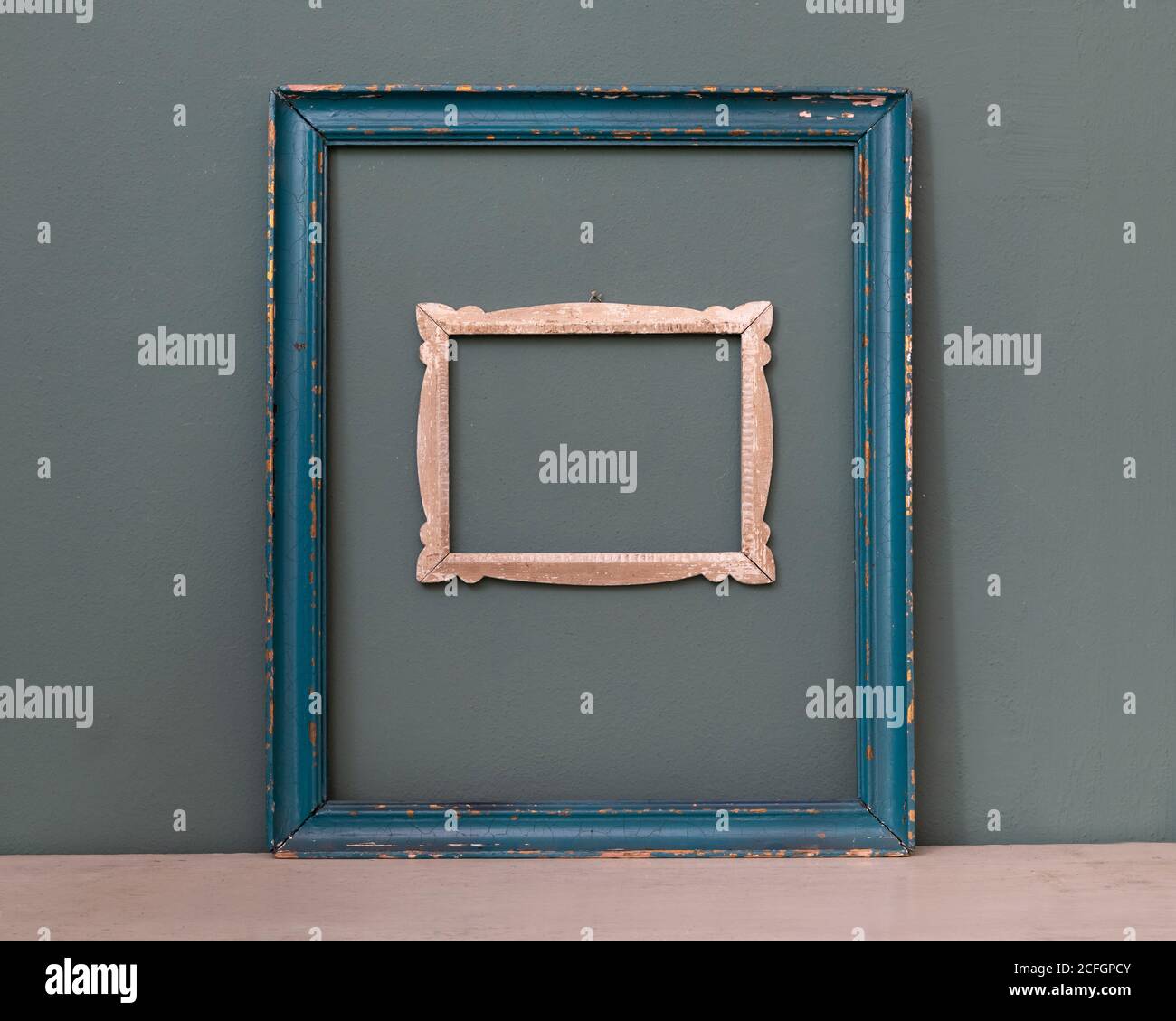 Deux cadres d'image vintage vides, l'un peint en bleu, l'autre un cadre sculpté plus petit accroché à un mur de couleur sarcelle pour la décoration intérieure Banque D'Images