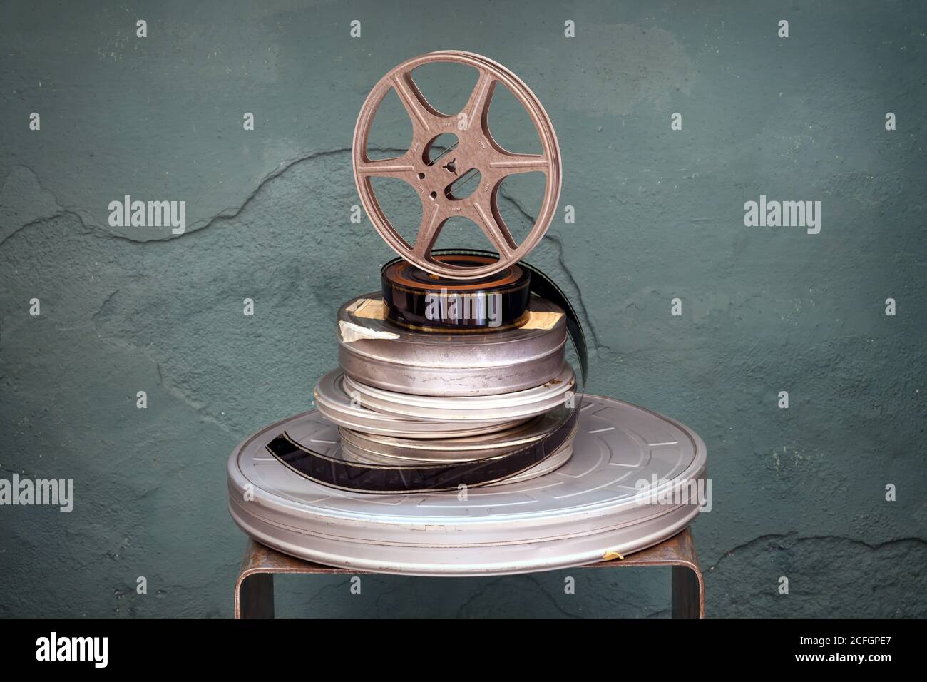 Vieux films d'époque empilés de diamètres variés avec un rouleau de projecteur debout sur un dessus vert texturé arrière-plan avec vignette Banque D'Images