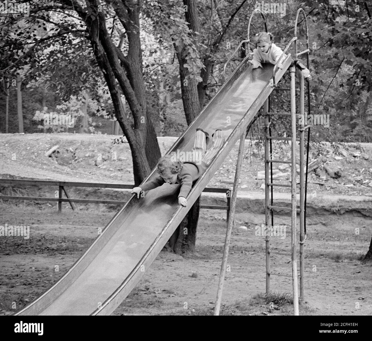 ANNÉES 1970 PETITE FILLE SŒUR GRIMPANT JUSQU'AU SOMMET ET GARÇON FRÈRE DESCENDANT LA TÊTE D'ABORD SUR LA GRANDE PLANCHE COULISSANTE DANS LE PARC DE JEUX - J13145 HAR001 HARS SCRAY SLIDE COMIC JOIE STYLE DE VIE FEMMES FRÈRES MAISON VIE COPIE ESPACE PLEINE LONGUEUR DANGER LES HOMMES RISQUENT SOUS-MARINS FRÈRES SŒURS B&W AVENTURE HUMORISTIQUE DÉCOUVERTE LOISIR ET LES LOISIRS PALPITANTS QUI SE GLISSENT DANS LE COMIQUE JUSQU'À LA SŒUR CONCEPT DAREDEVIL COMÉDIE TÊTE PREMIÈRE JUVÉNILES TOGETHERNESS NOIR ET BLANC ORIGINE ETHNIQUE CAUCASIENNE HAR001 À L'ANCIENNE Banque D'Images