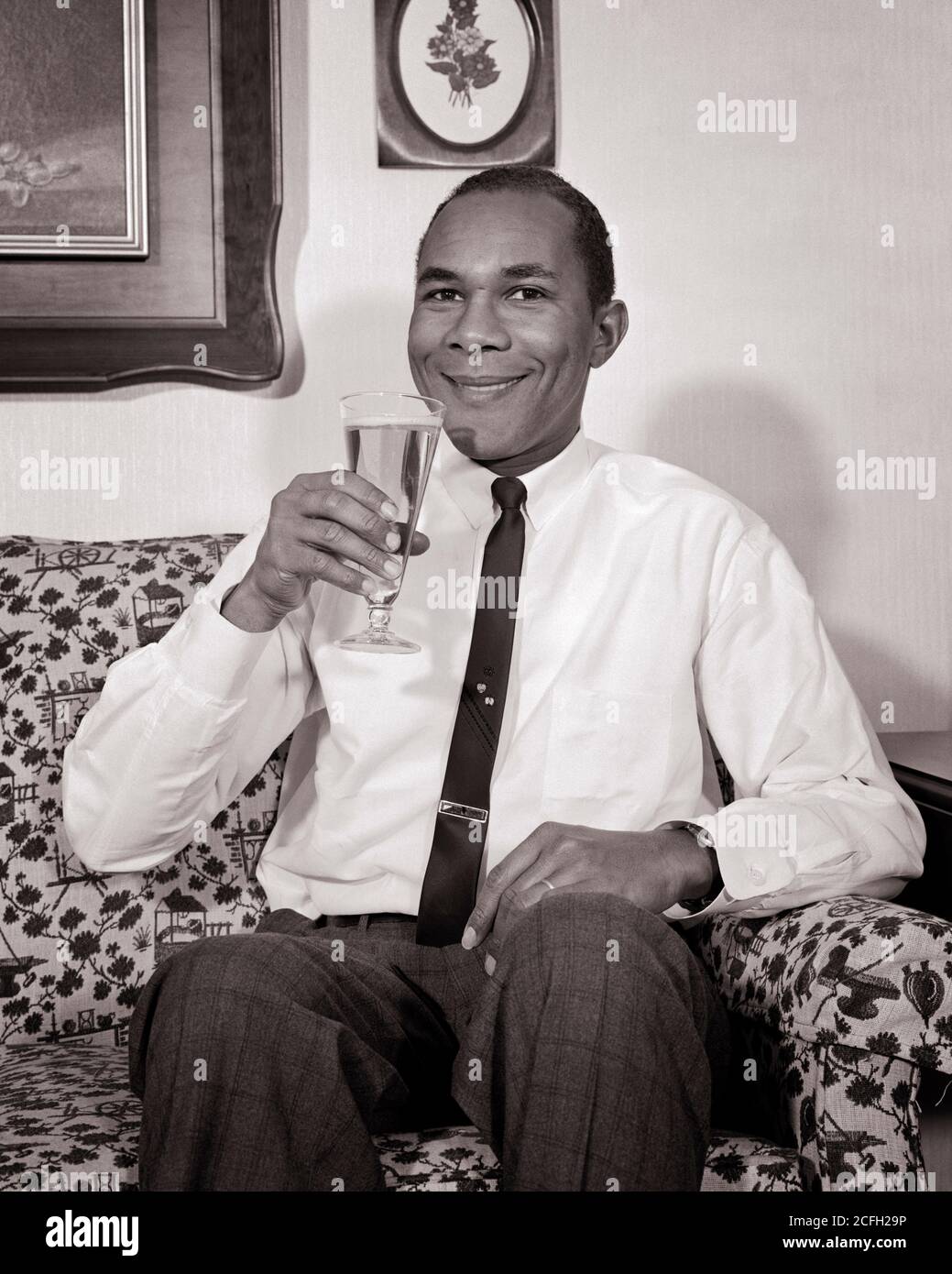HOMME AFRO-AMÉRICAIN DES ANNÉES 60 SOURIANT ASSIS SUR UN CANAPÉ BUVANT DU VERRE PILSNER BIÈRE PORTANT SHIRTSLEEVES CRAVATE REGARDER LA CAMÉRA - N1830 HAR001 HARS PERSONNES HOMMES CONFIANCE B&W CONTACT VISUEL BONHEUR GAI BOISSON LOISIRS AFRO-AMÉRICAINS FLUIDE AFRO-AMÉRICAIN RELALXD NOIR FIERTÉ ETHNIQUE CRAVATE SOURIRES PILSNER CONSOMMER L'HYDRATATION JOYEUSE ÉLÉGANT SHIRTSLEEVES BREWSKI ADULTE MOYEN-ADULTE HOMME RAFRAÎCHISSANT DÉTENTE À LA MAISON BOISSONS NOIR ET BLANC HAR001 AFRO-AMÉRICAINS À L'ANCIENNE Banque D'Images