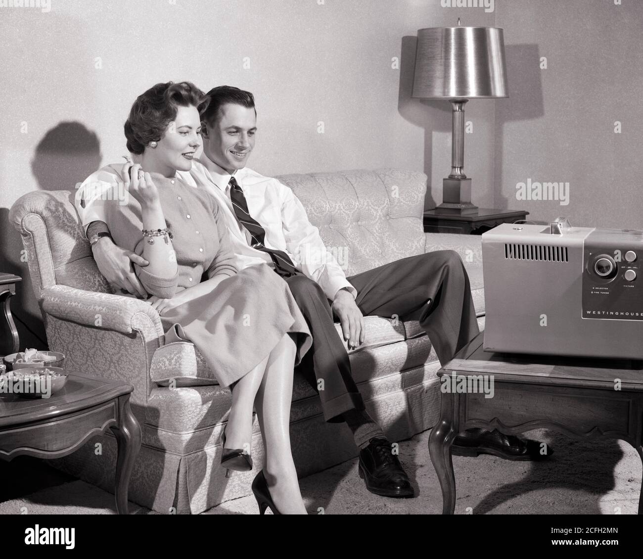 ANNÉES 1950 COUPLE CONTENT HOMME FEMME MARI FEMME ASSIS SUR UN CANAPÉ DANS LE SALON FUMEUR REGARDANT LA TÉLÉVISION PORTABLE - R518 HAR001 HARS COUCH COMMUNICATION PAIX ÉQUILIBRE INFORMATION HEUREUX JOIE STYLE DE VIE SATISFACTION FEMMES MARIÉE CONJOINT ÉPOUX VIE À LA MAISON COPIE ESPACE PLEINE LONGUEUR FEMMES PERSONNES HOMMES DIVERTISSEMENT PORTABLE B&W PARTENAIRE GRAND ANGLE RÊVES BONHEUR GAI PROTECTION RÉSEAU CHOIX EXCITATION DIVERTISSEMENT SUR LES SOURIRES CONNEXION ENGROSED CONCEPTUEL JOYFUL ÉLÉGANT CONTENTED MI-ADULTE MOYEN-ADULTE HOMME MOYEN-ADULTE FEMME RELAXATION TOGETHERNESS FEMMES ABSORBAIENT NOIR ET BLANC Banque D'Images