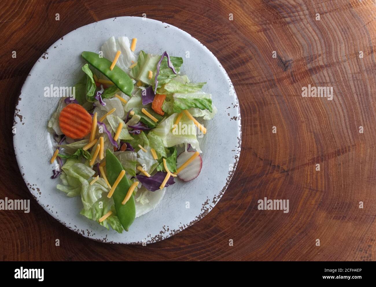 Une salade mixte sur une assiette ronde blanche, avec un fond d'une coupe  transversale d'un tronc d'arbre avec des anneaux d'arbre Photo Stock - Alamy