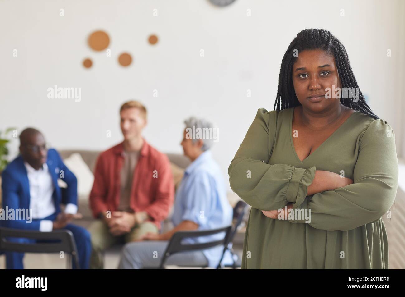 Portrait à la taille de la jeune femme afro-américaine regardant l'appareil photo avec des gens assis en cercle en arrière-plan, le concept de groupe de soutien, l'espace de copie Banque D'Images