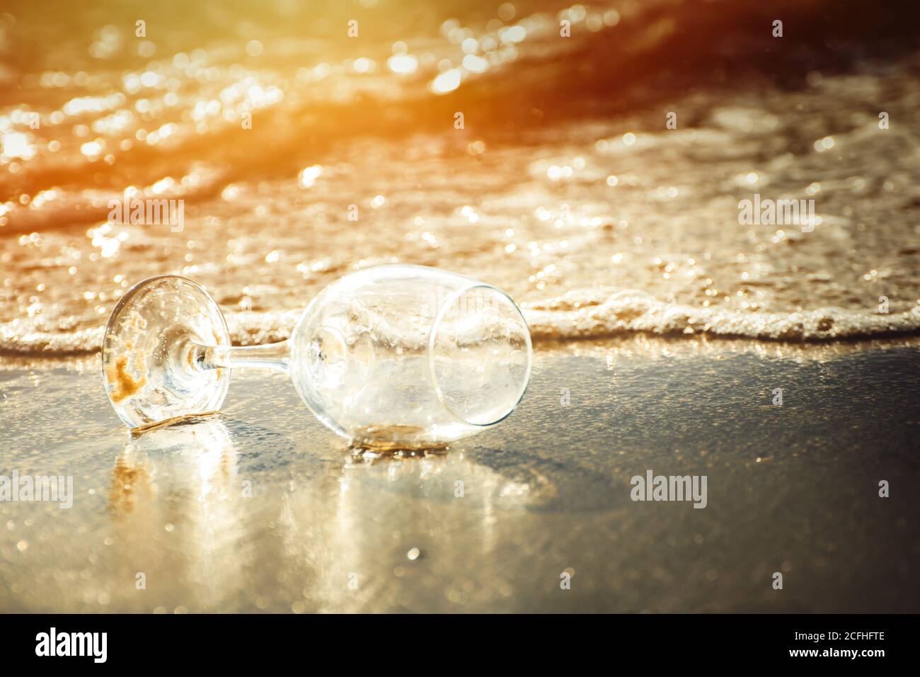 vin de verre sur la plage et eau de mer affluer heure d'or Banque D'Images