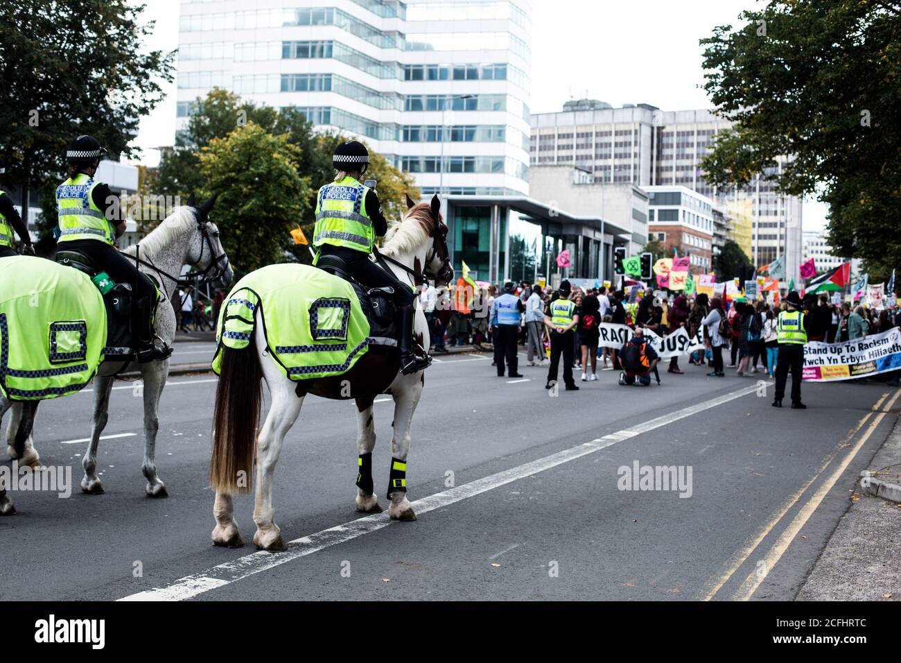 Les policiers sur les chevaux de police se rassemblent devant les manifestants Banque D'Images