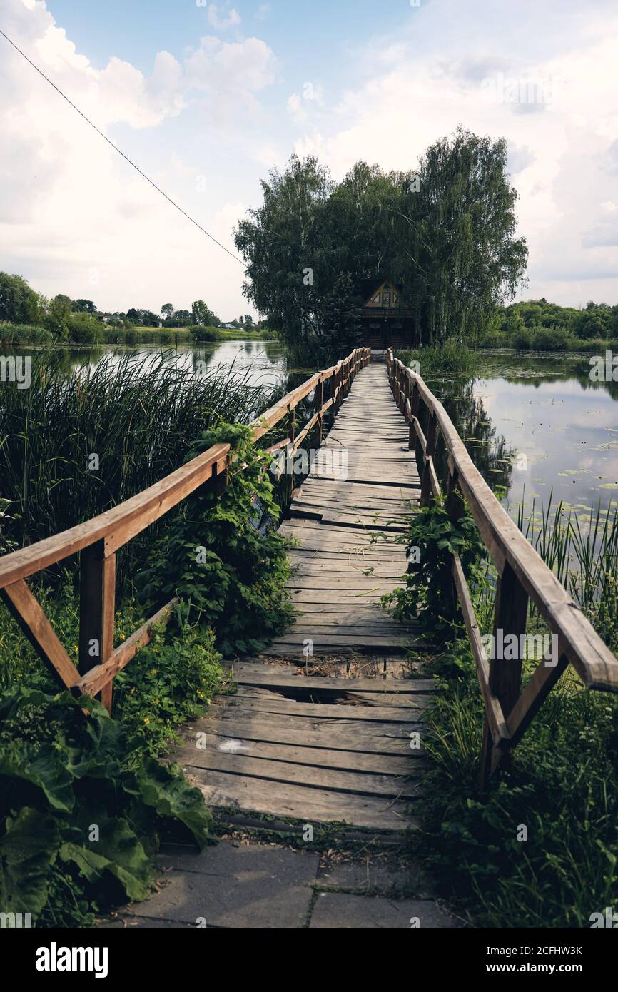 Vue sur le paysage du vieux petit pont en bois de l'autre côté du lac. Fishman maison sur une île entourée de wither et de forêt Banque D'Images