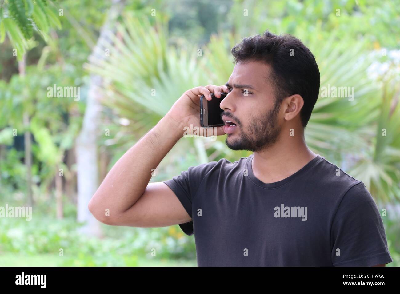 Portrait d'un jeune homme parlant sur téléphone mobile et il a l'air choqué Banque D'Images