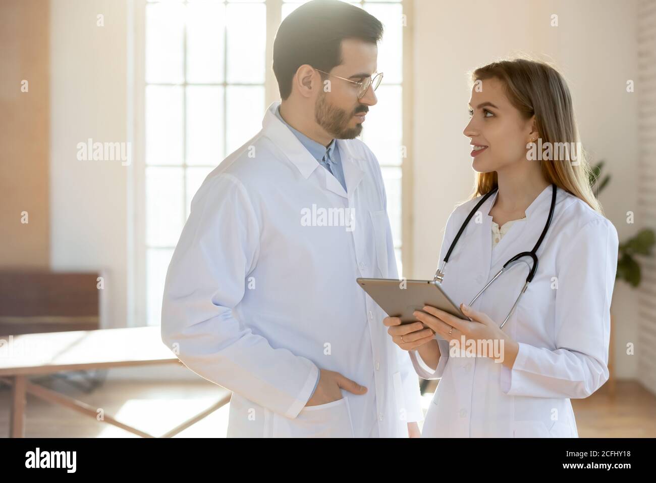 Jeune infirmière souriante et médecin parlant au bureau, travaillant ensemble Banque D'Images