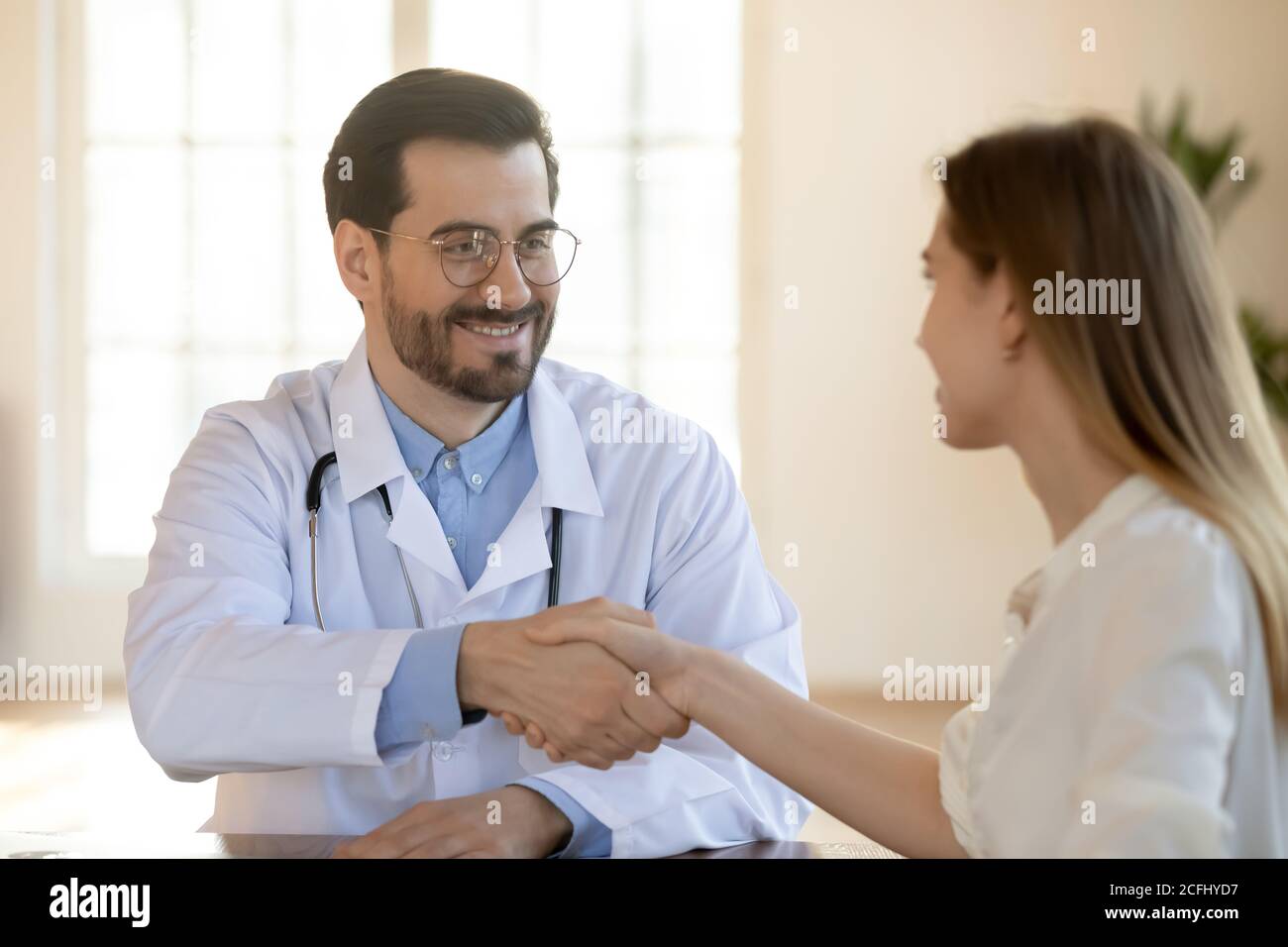 Un médecin souriant se secouant la main du patient lors de la réunion Banque D'Images