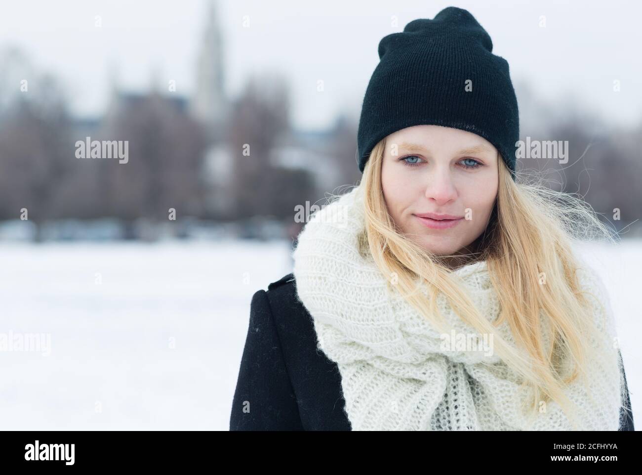 Belle jeune femme blonde vêtue d'une tenue d'hiver dans la neige de la ville d'Europe. Gros plan portrait. Banque D'Images