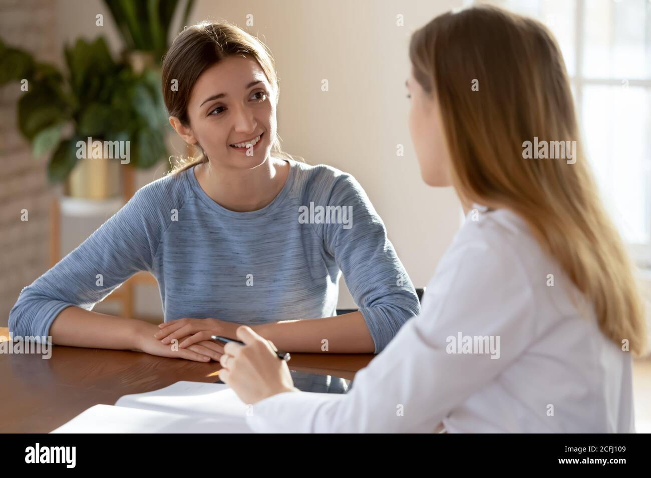 Jeune femme souriante, patiente à l'écoute du médecin lors de la réunion Banque D'Images