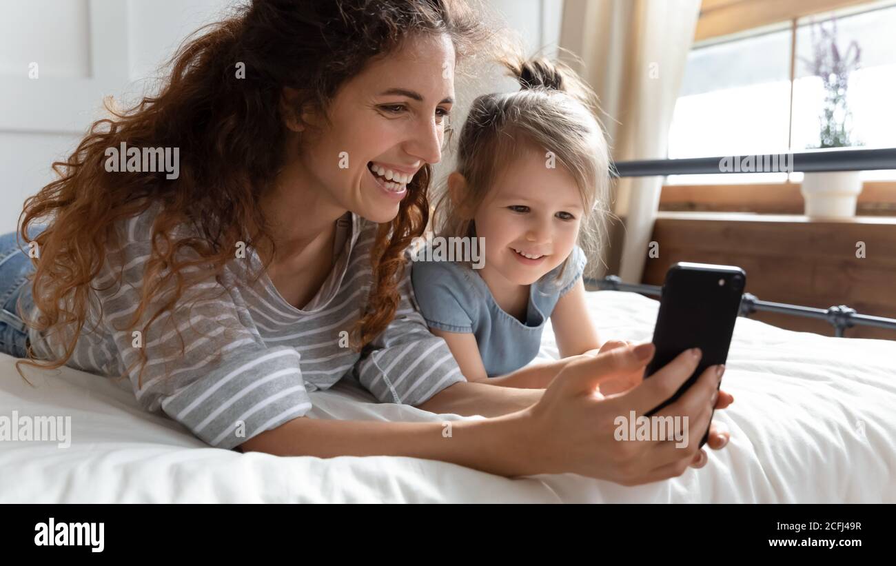 Couché sur le lit de la mère et de la fille à l'aide d'un smartphone faisant la vidéo Banque D'Images