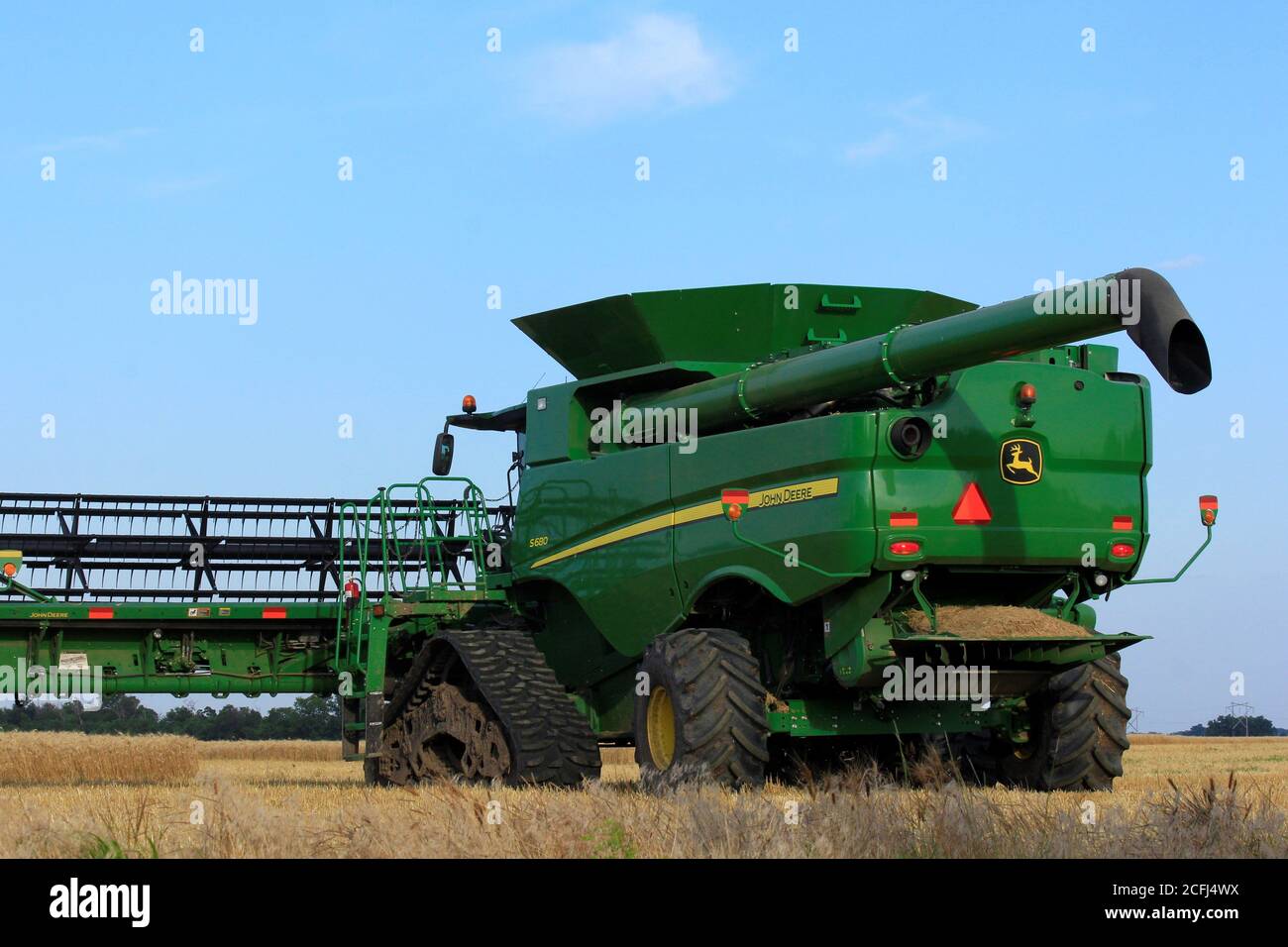 John Deere coupe du blé dans un champ de ferme du Kansas dans le pays avec un ciel bleu. Banque D'Images