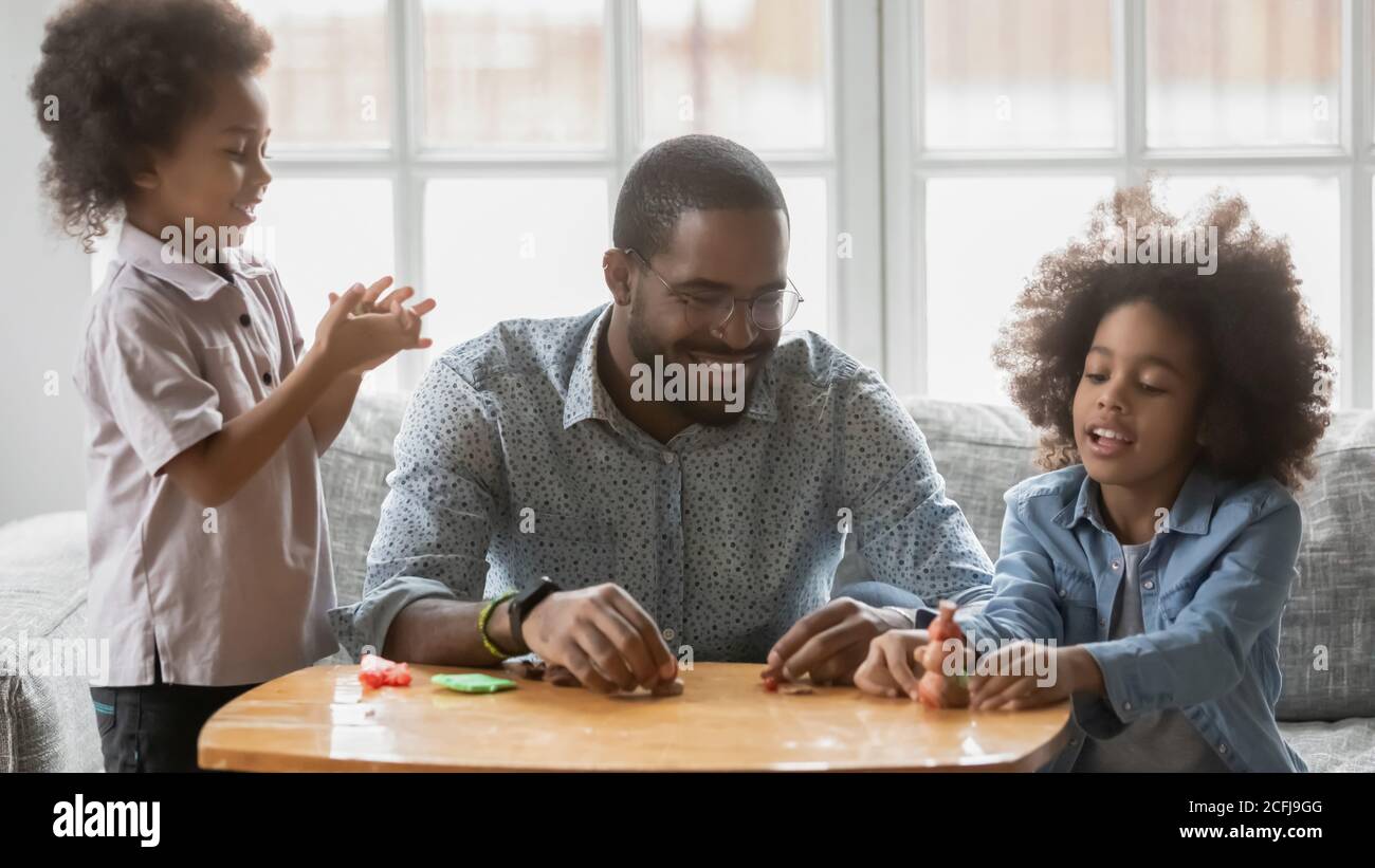 Joyeux jeune père ethnique africain jouant avec de la plaline avec des enfants. Banque D'Images