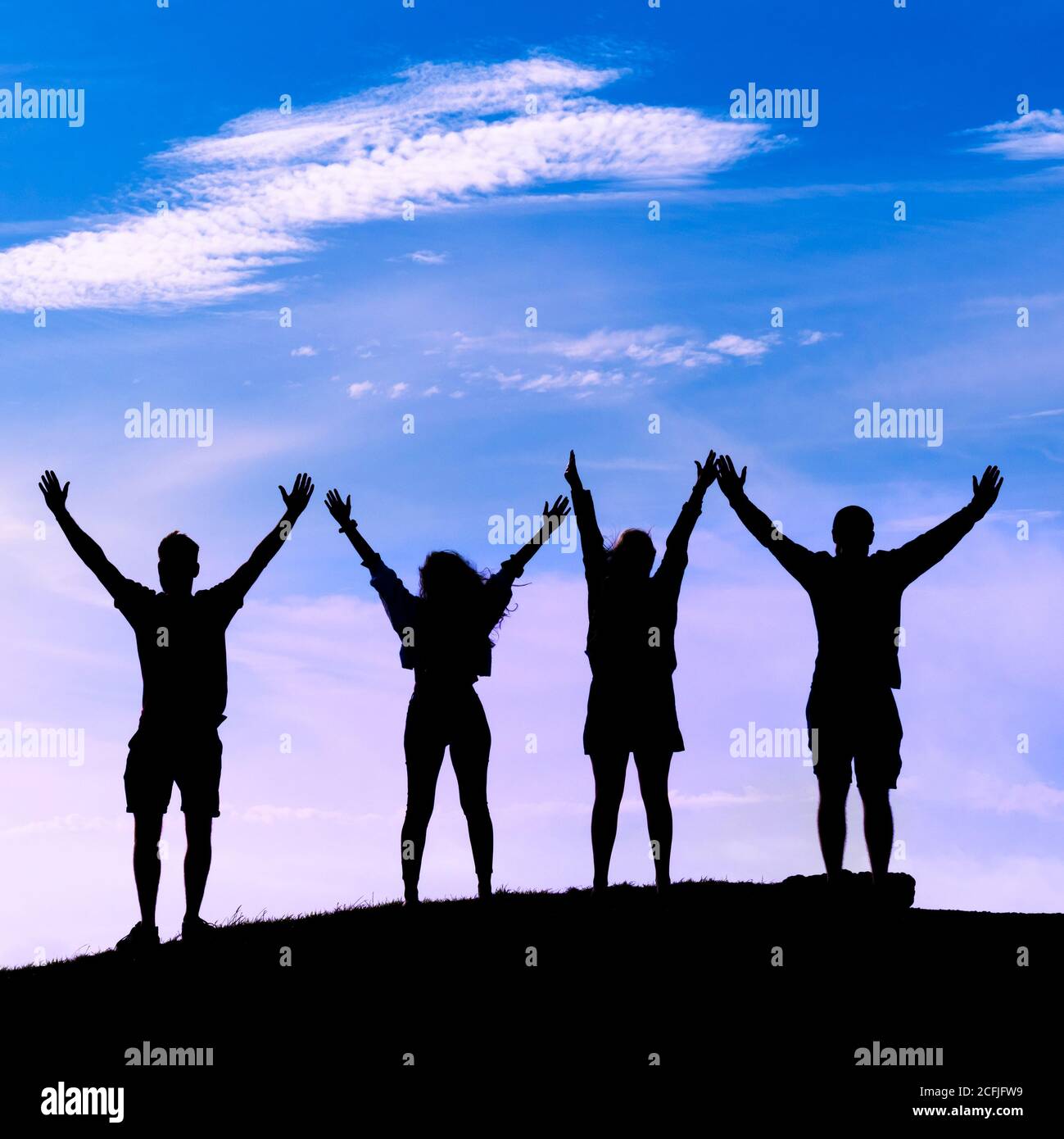 Un groupe de quatre vacanciers vus en silhouette debout Le sommet de Pentire point East et de célébrer dans le Soleil en fin de soirée à Newquay Banque D'Images