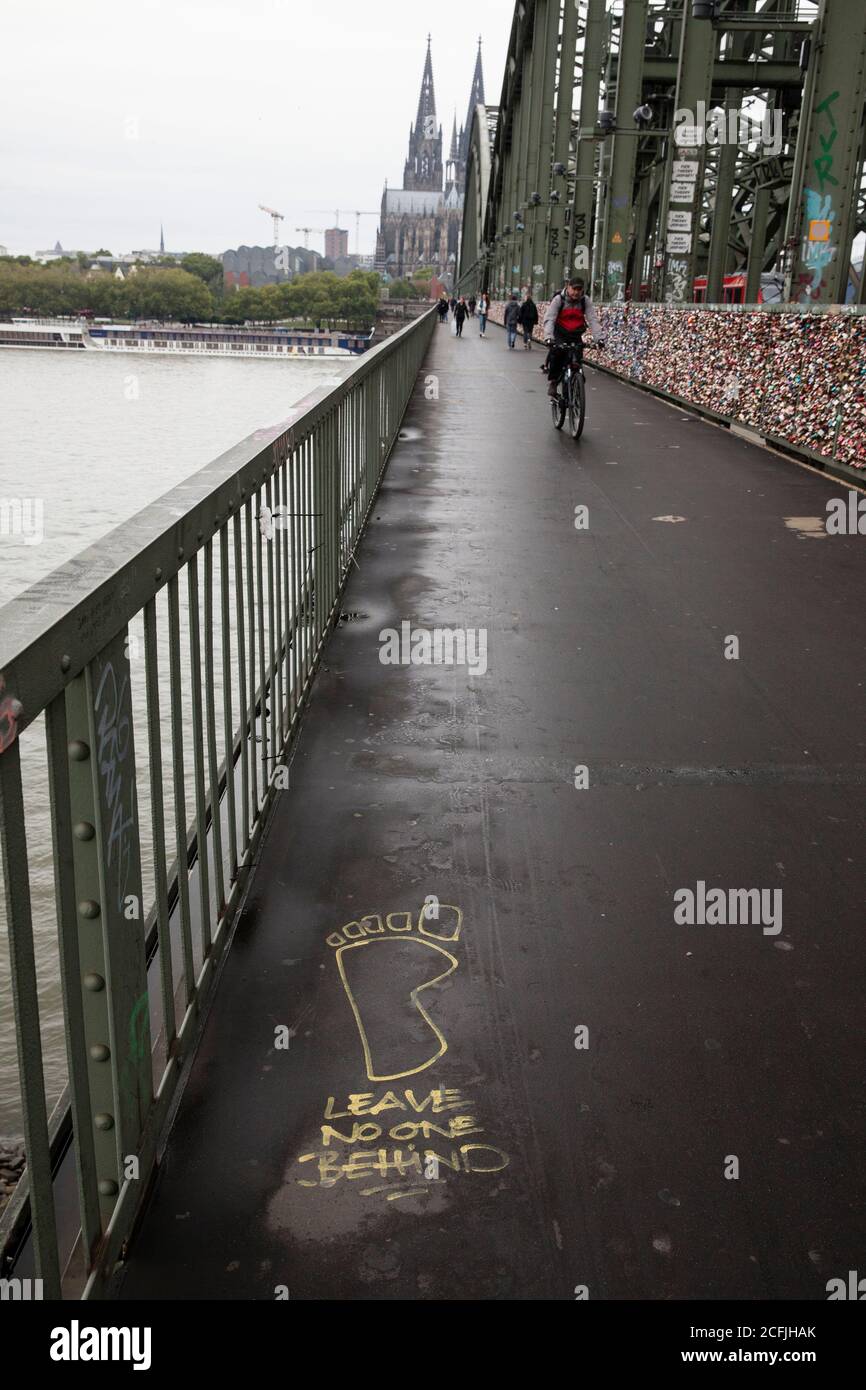 graffiti 'ne laissez personne derrière' sur le pont de chemin de fer Hohenzollern, vue sur la cathédrale, Cologne, Allemagne. Graffitis « ne laissez personne derrière vous » auf der Banque D'Images