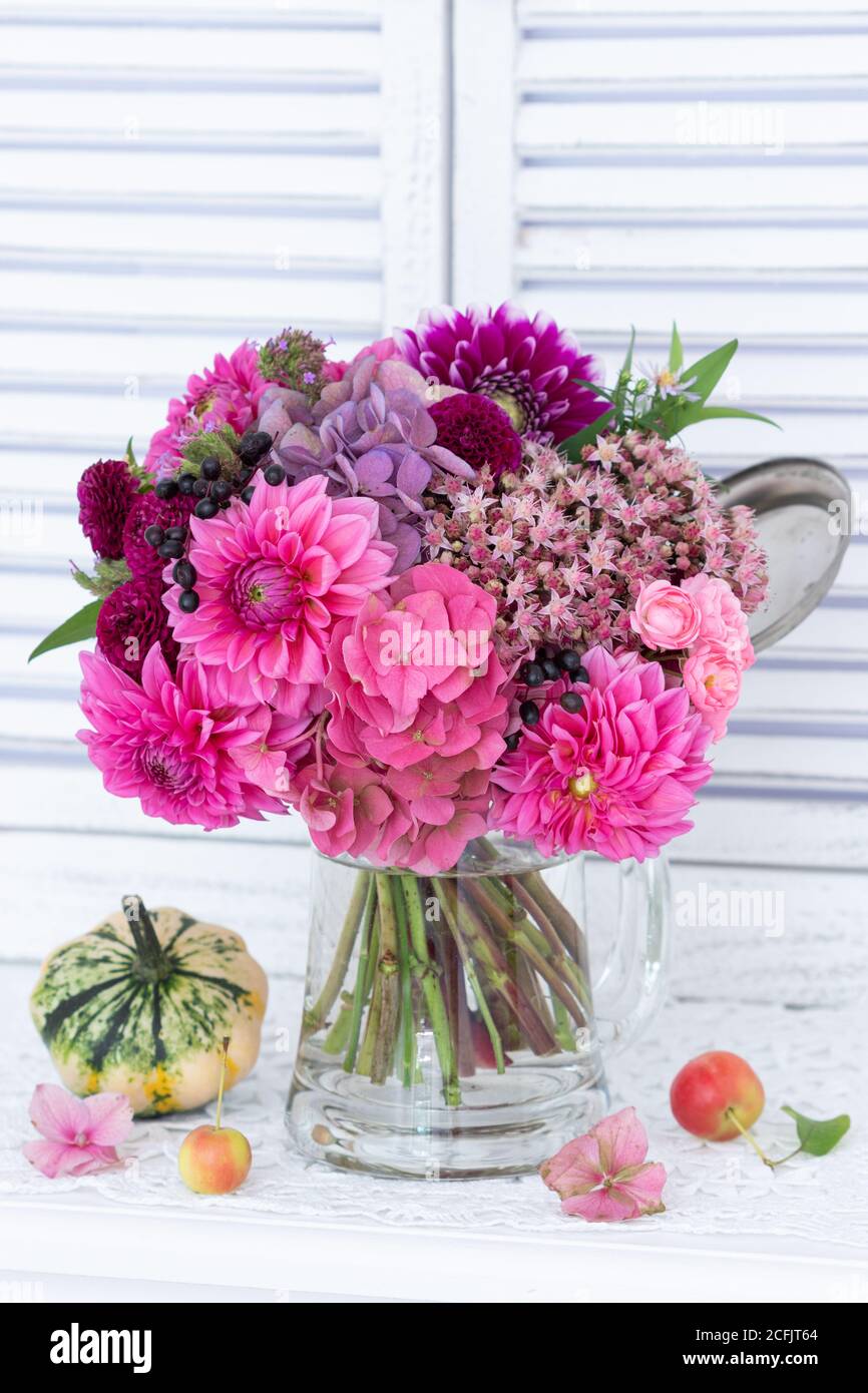 bouquet romantique de dahlias roses, fleurs d'hortensia et récolte de pierre dans une tasse de bière en verre Banque D'Images