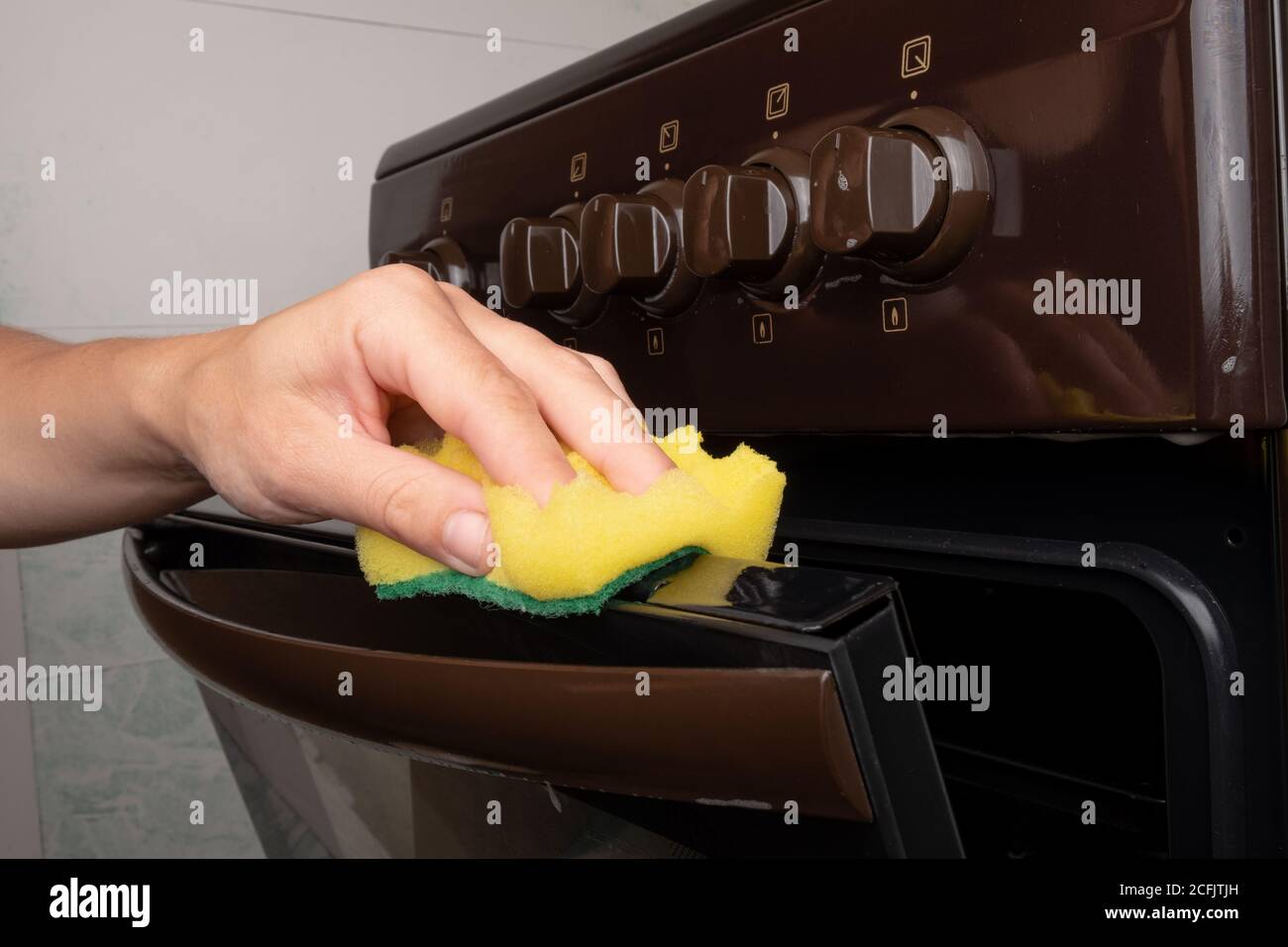 nettoyage de la surface d'un four à gaz à l'aide d'une lavette jaune, nettoyage de la cuisine. Banque D'Images