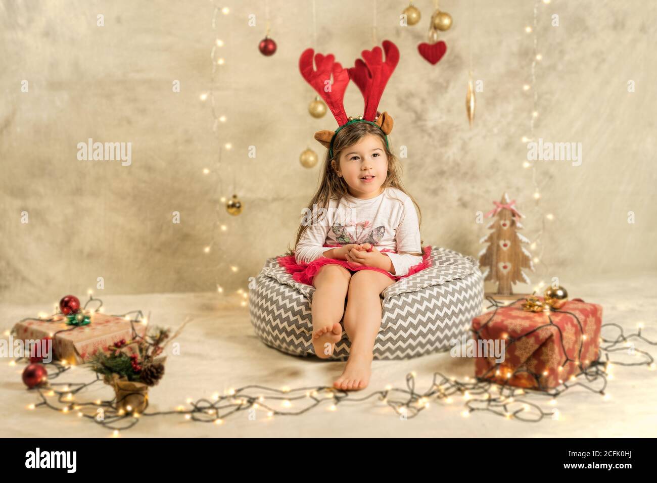 Photographie studio de Noël d'une petite fille adorable portant un bandeau  de renne. Fond beige festif avec cadeaux, boules de Noël et lumières Photo  Stock - Alamy