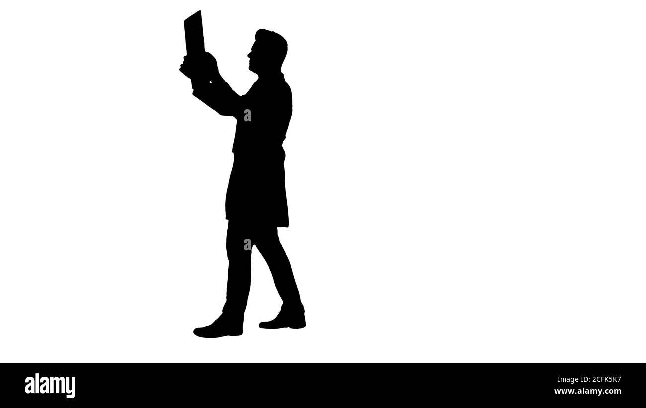 Le personnel de Silhouette Healthcare, sous une couche blanche, regarde l'image radiographique à rayons X, l'acquisition ct, l'irm tout en marchant. Banque D'Images