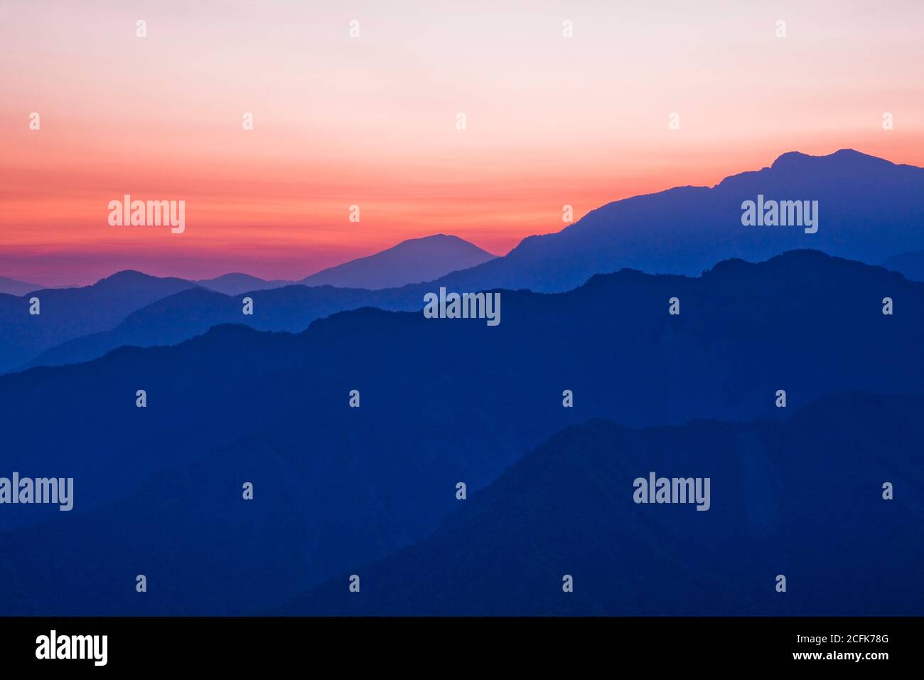 Des couches de magnifiques montagnes au lever du soleil avec des nuages colorés en arrière-plan Banque D'Images