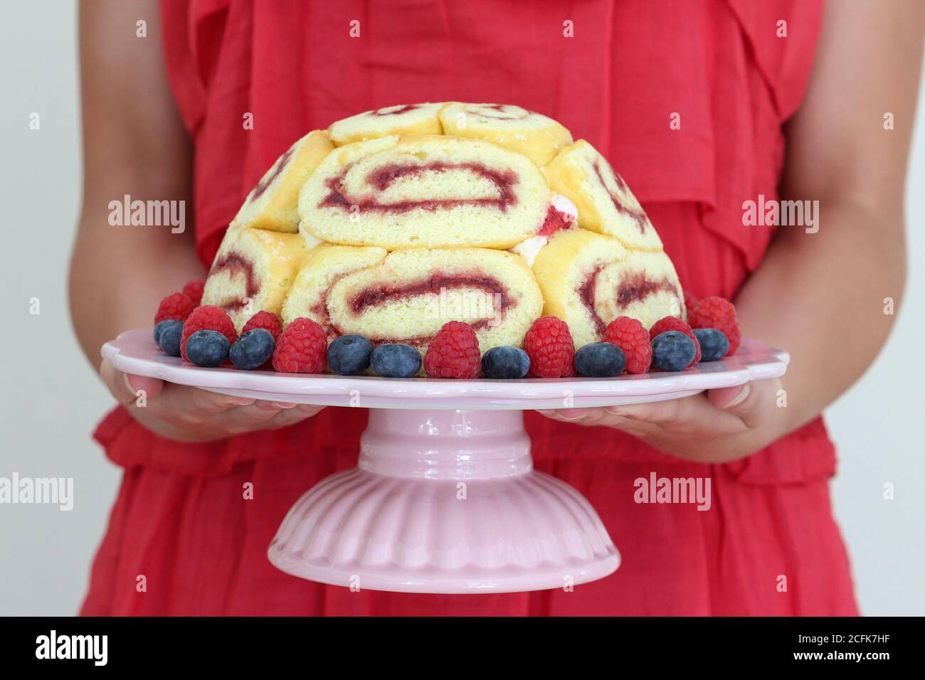 gâteau charlotte avec myrtilles et fraises et assiette à gâteau mains des femmes Banque D'Images