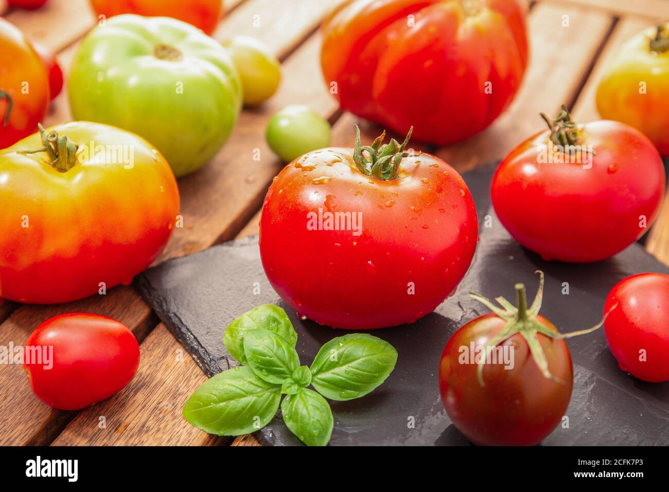 Variété de tomates biologiques sur une table en bois Banque D'Images