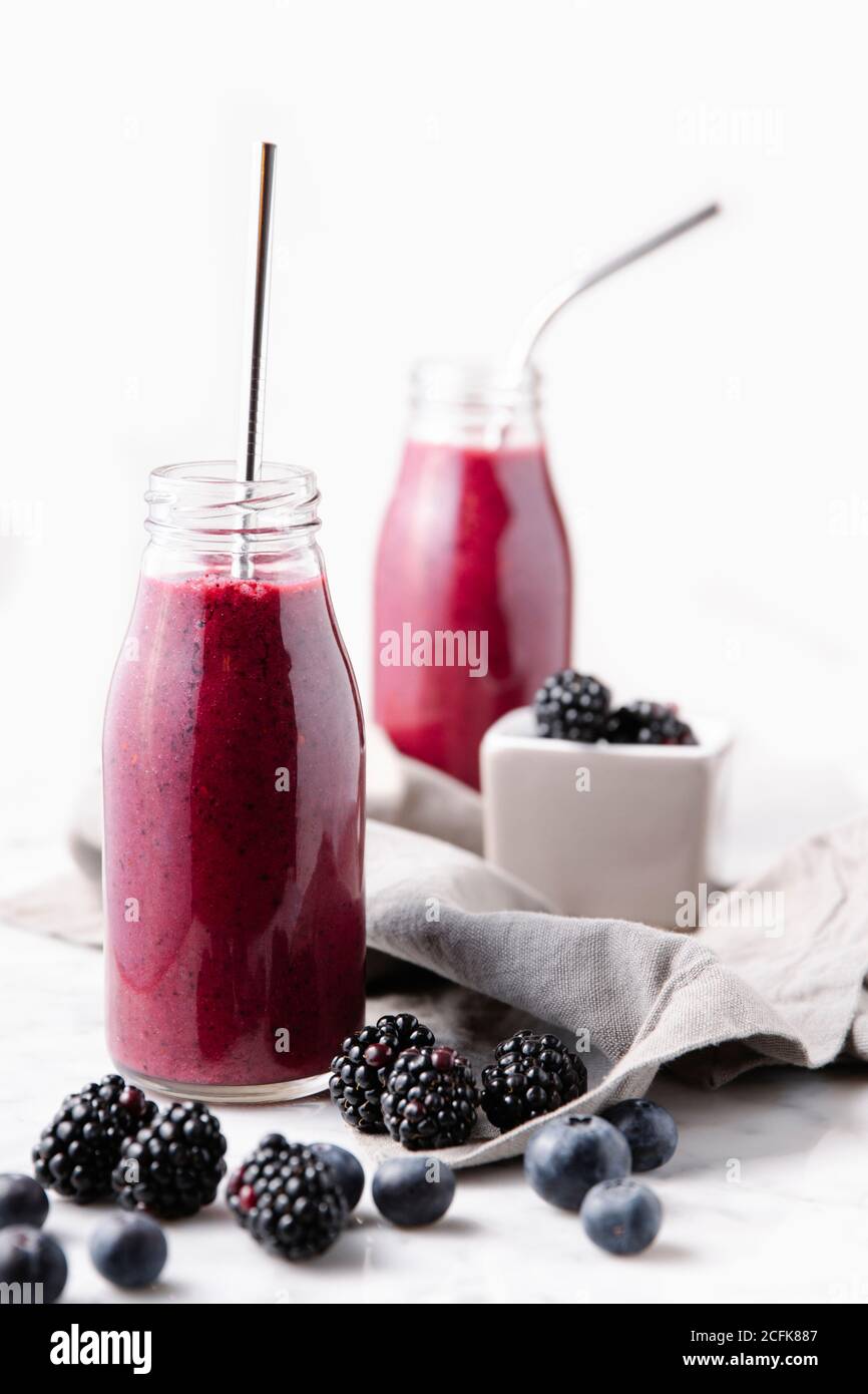 Smoothie aux baies en bouteilles de verre avec pailles métalliques réutilisables. Vue verticale avant. Banque D'Images